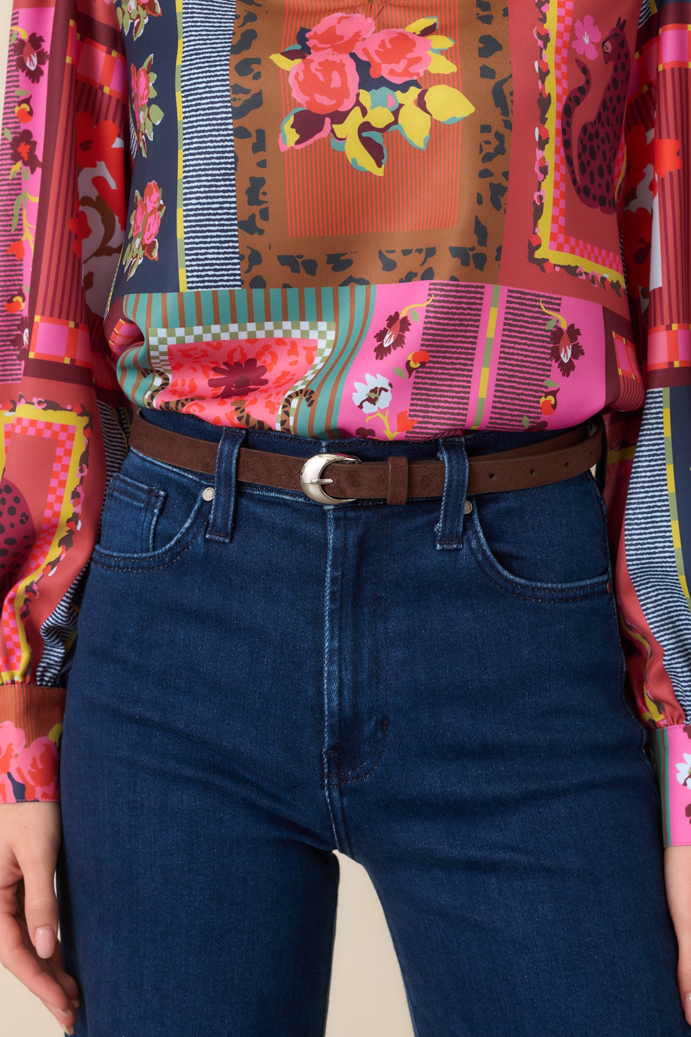 Slim brown faux suede belt featuring a curved silver-tone buckle and smooth, polished finish with subtle western-inspired styling.