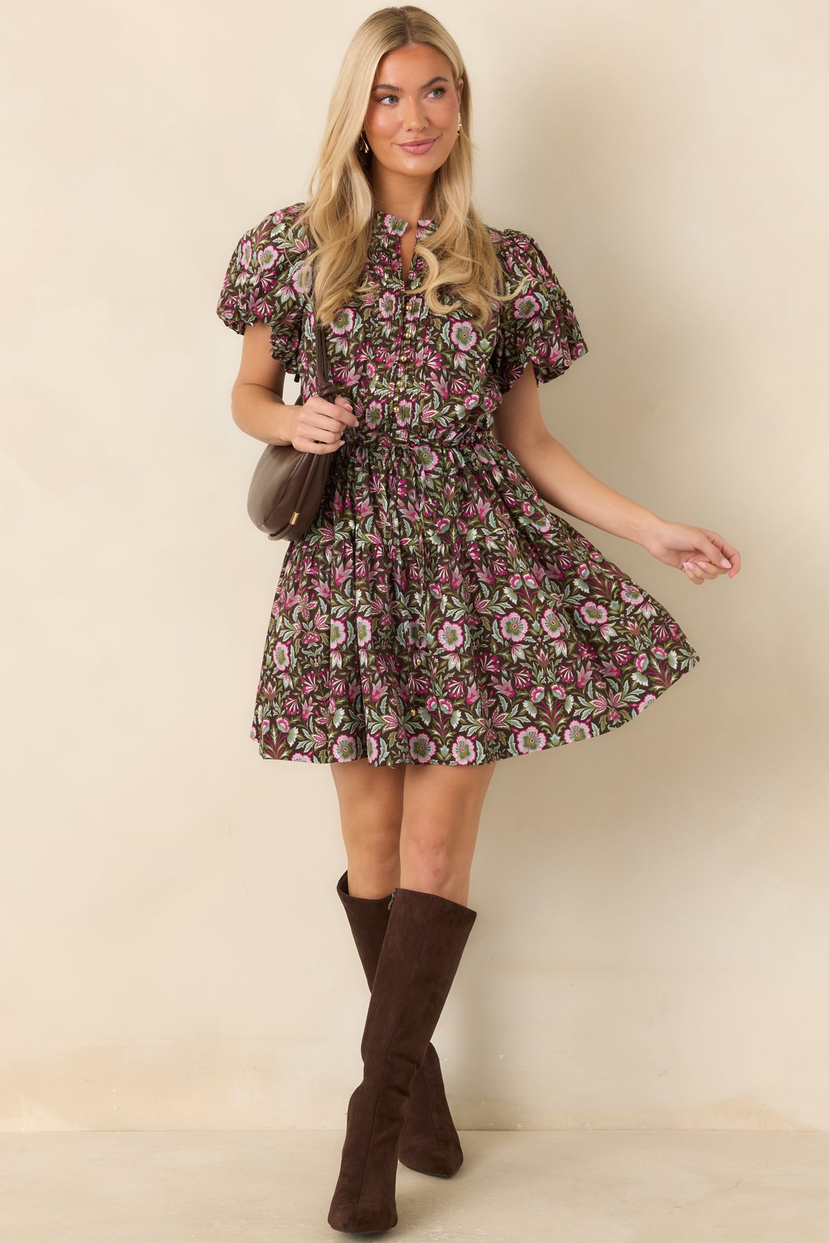 Brown mini dress showcases vibrant pink and green florals, gold-tone buttons, pleated front detailing, and an adjustable drawstring waist.