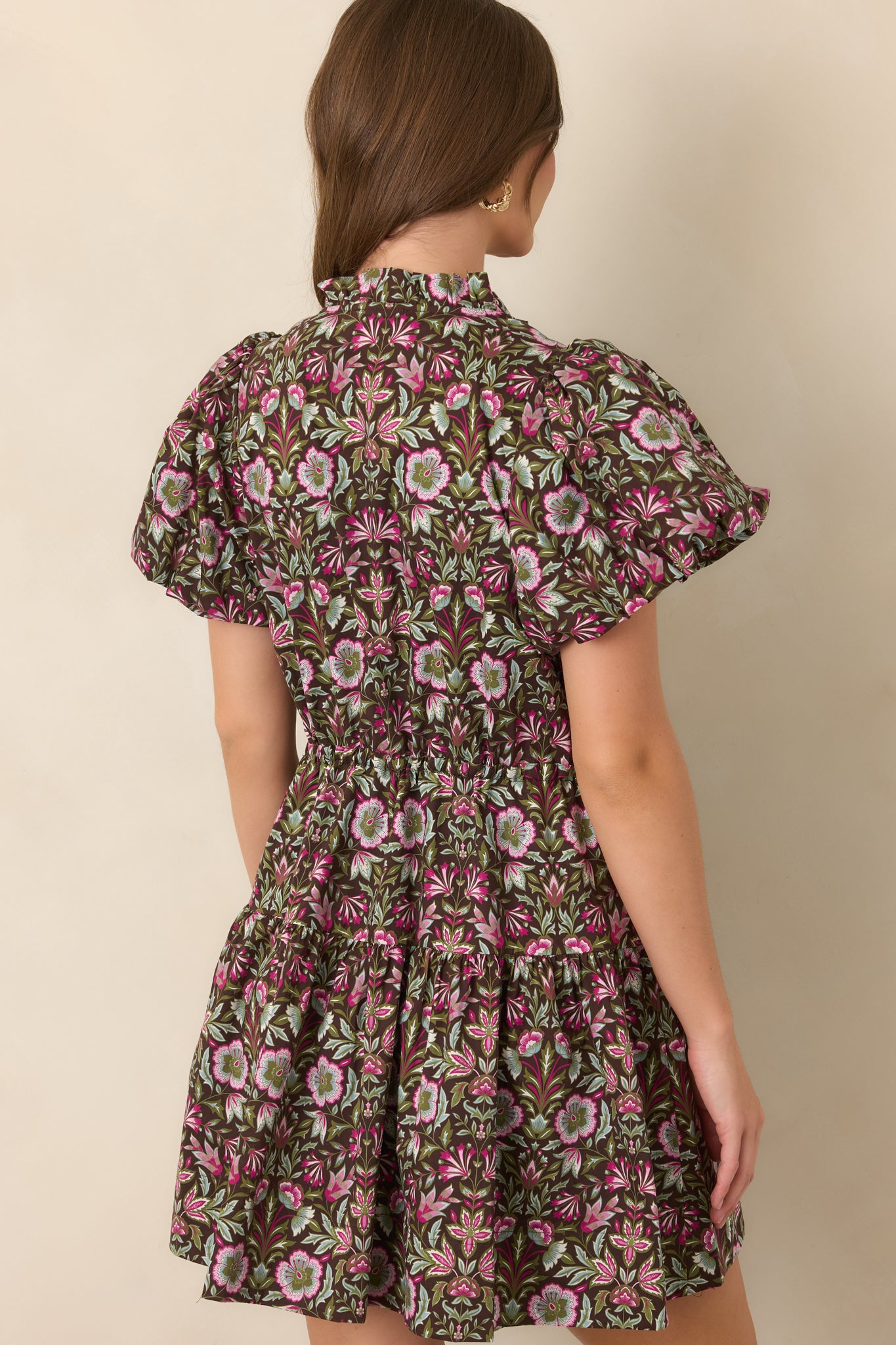 Rear view of the brown floral mini dress showing its flutter sleeves, adjustable waist, and softly tiered skirt.