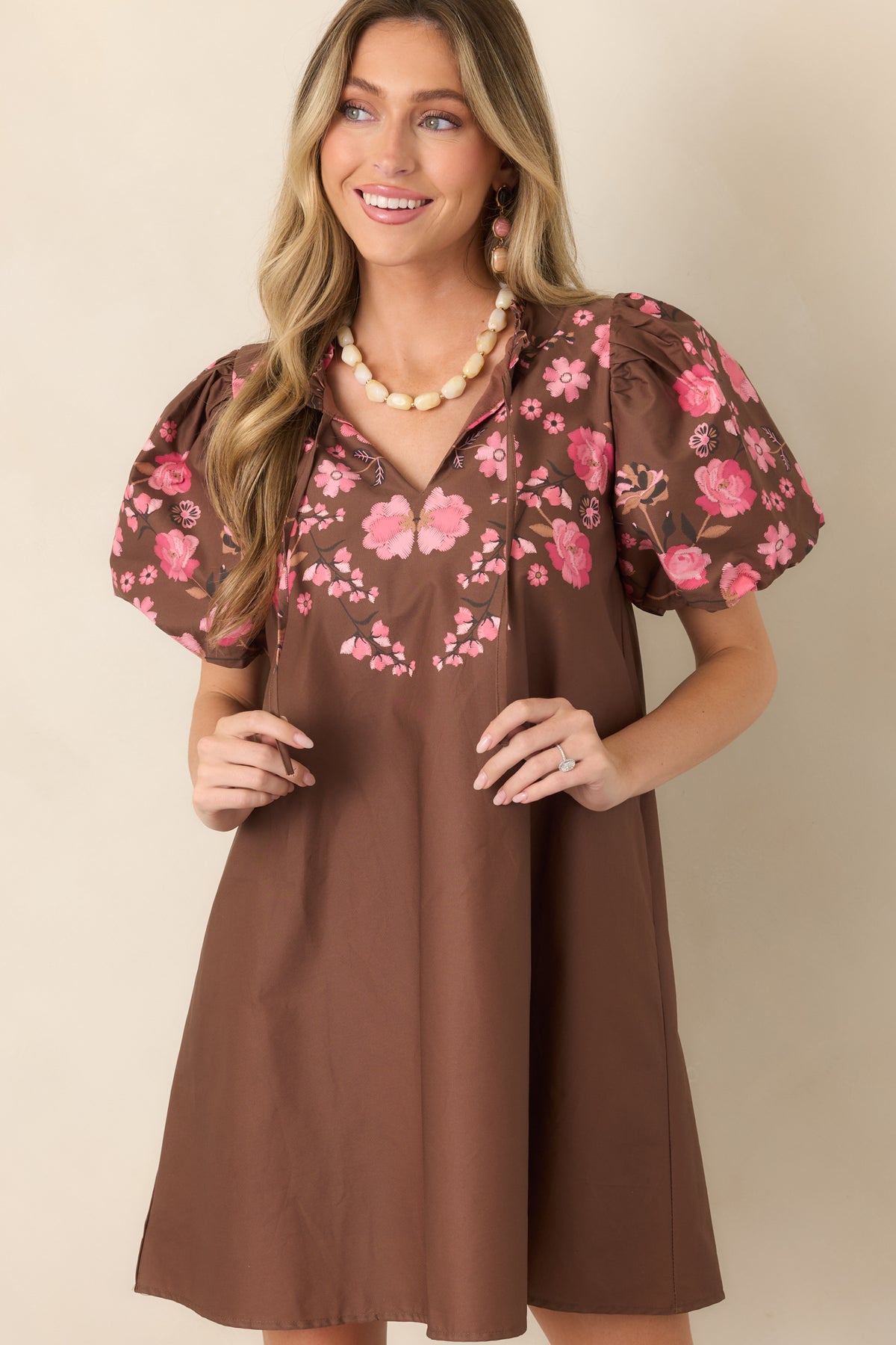 Detailed view of the dress’s romantic floral pattern, ruffle-edged neckline, and softly voluminous puff sleeves.