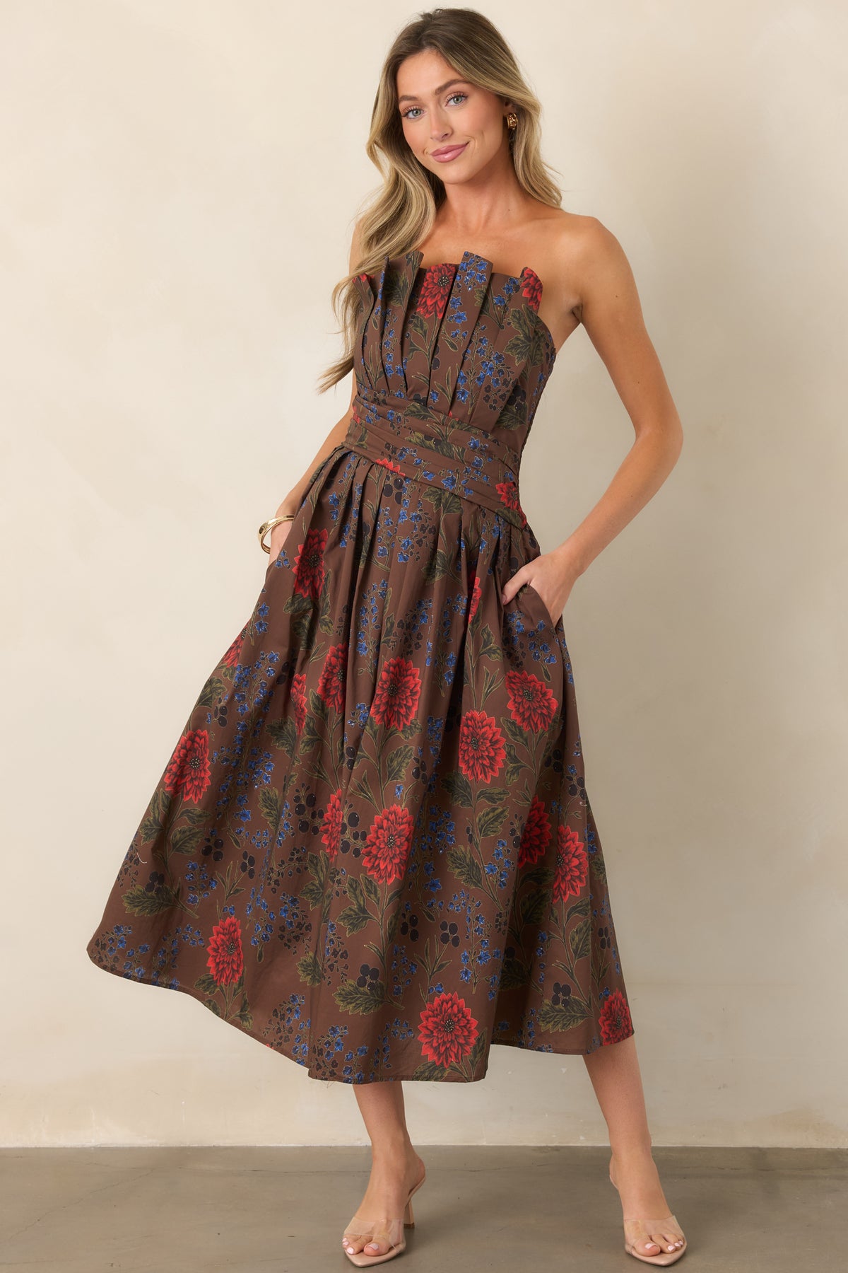 Angled view of a brown floral strapless midi dress with structured bodice pleats and a full skirt.
