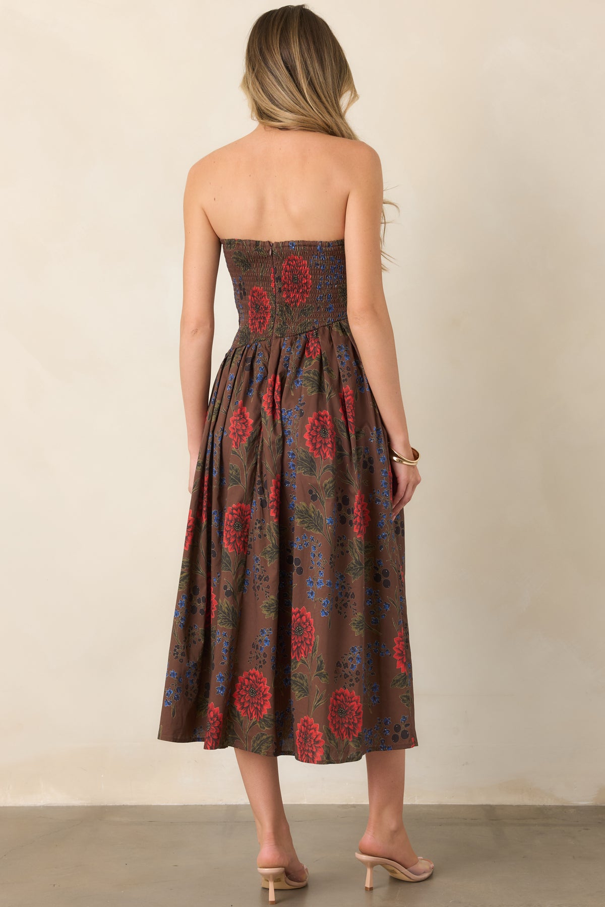 Back view of a brown floral strapless midi dress with a smocked back bodice and full pleated skirt.