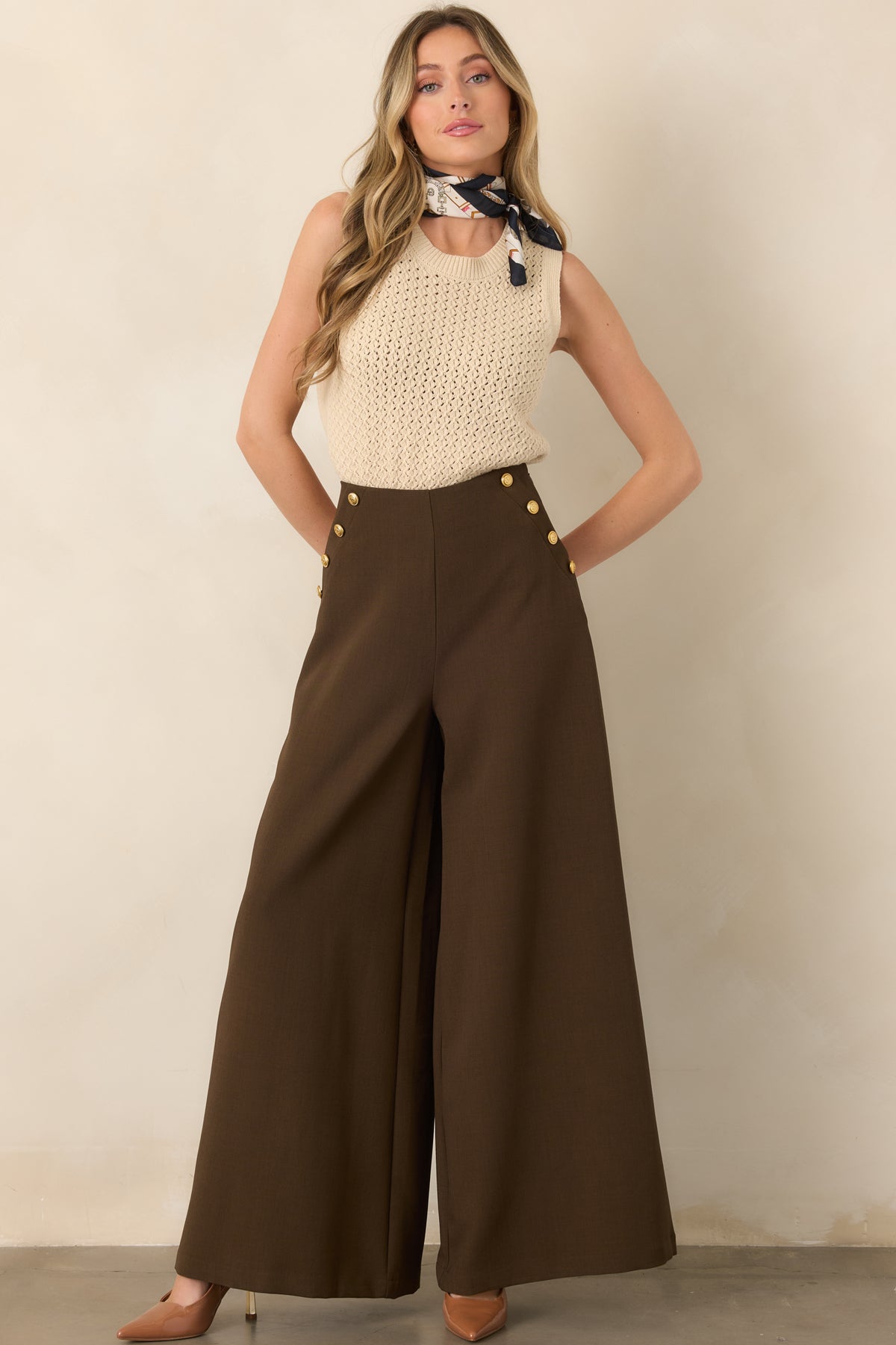 Rich brown woven trousers showcasing decorative gold buttons along each hip, a structured high waist, and elegant wide legs.