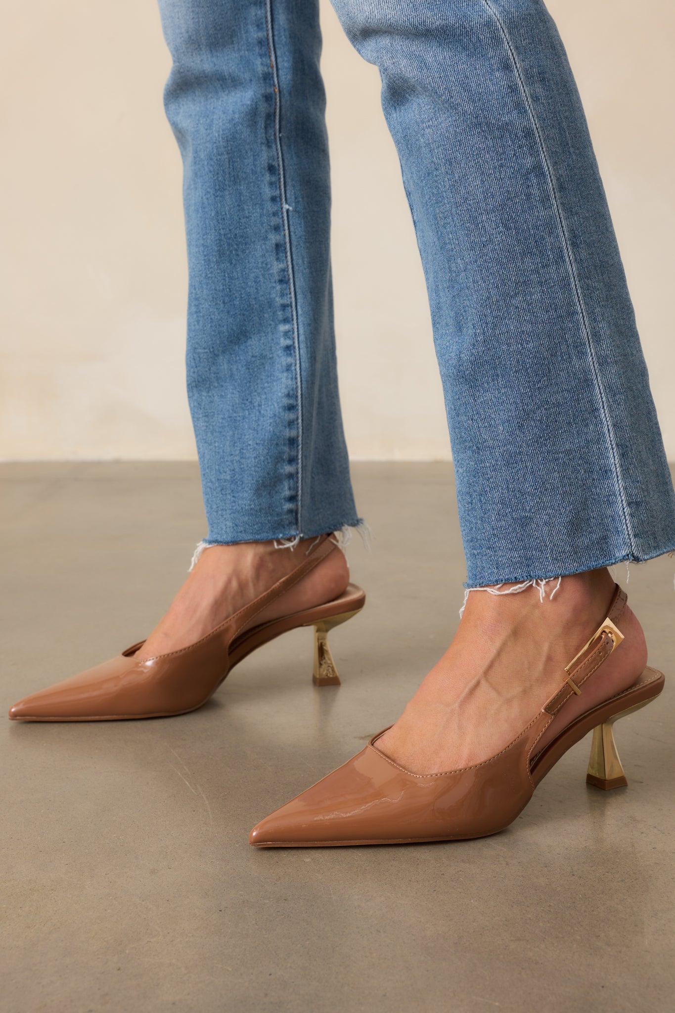 Cropped angle of the brown heels emphasizing the gold kitten heel and pointed toe.