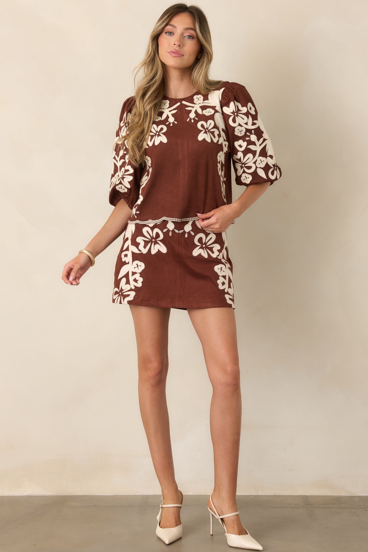 Warm brown mini skirt with ivory floral detailing and a gently flared silhouette for a vintage-inspired finish.
