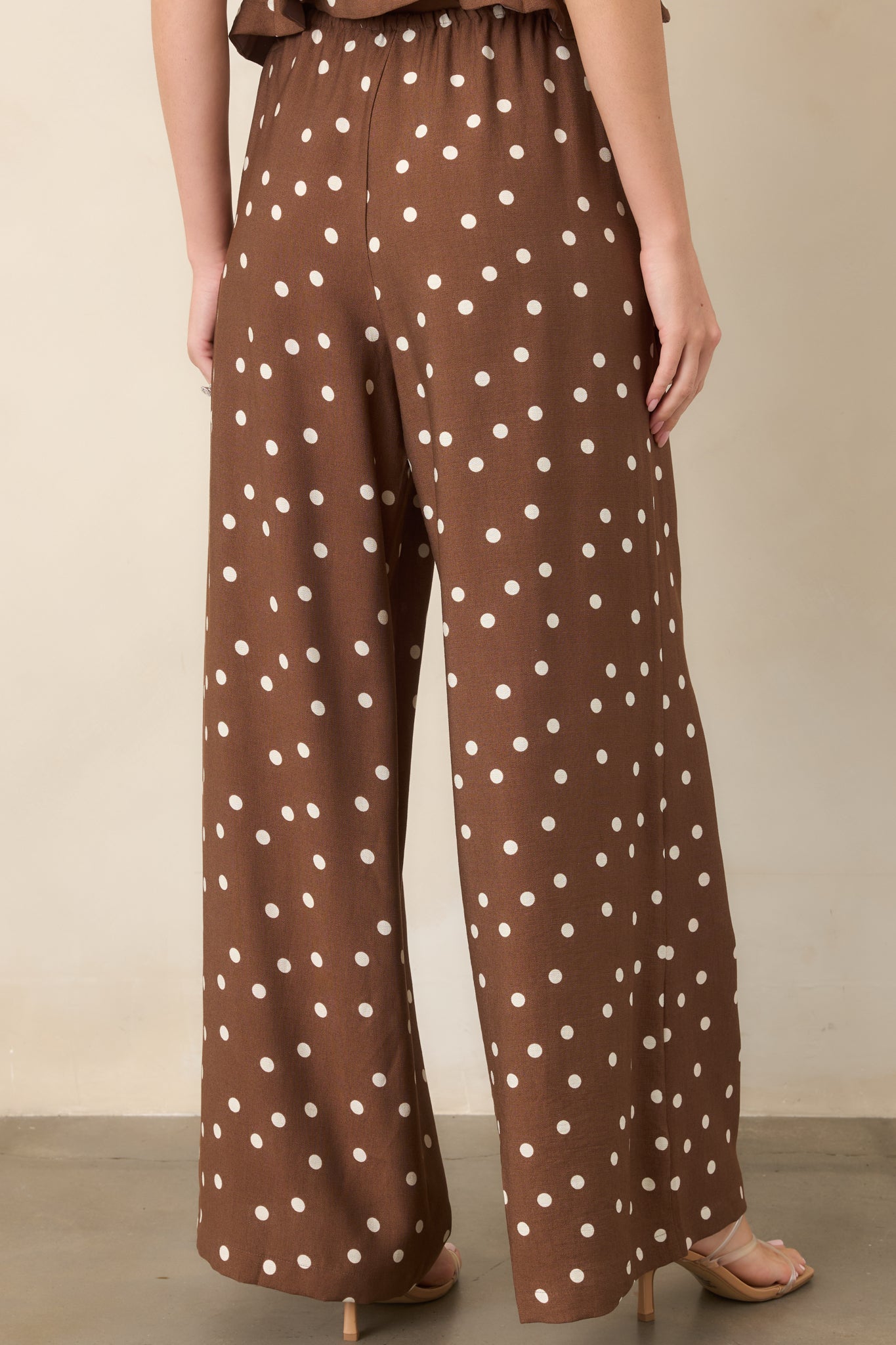 Rear view of the brown and ivory polka dot pants showcasing the relaxed wide-leg silhouette, drawstring waistband, and flowing unlined construction.
