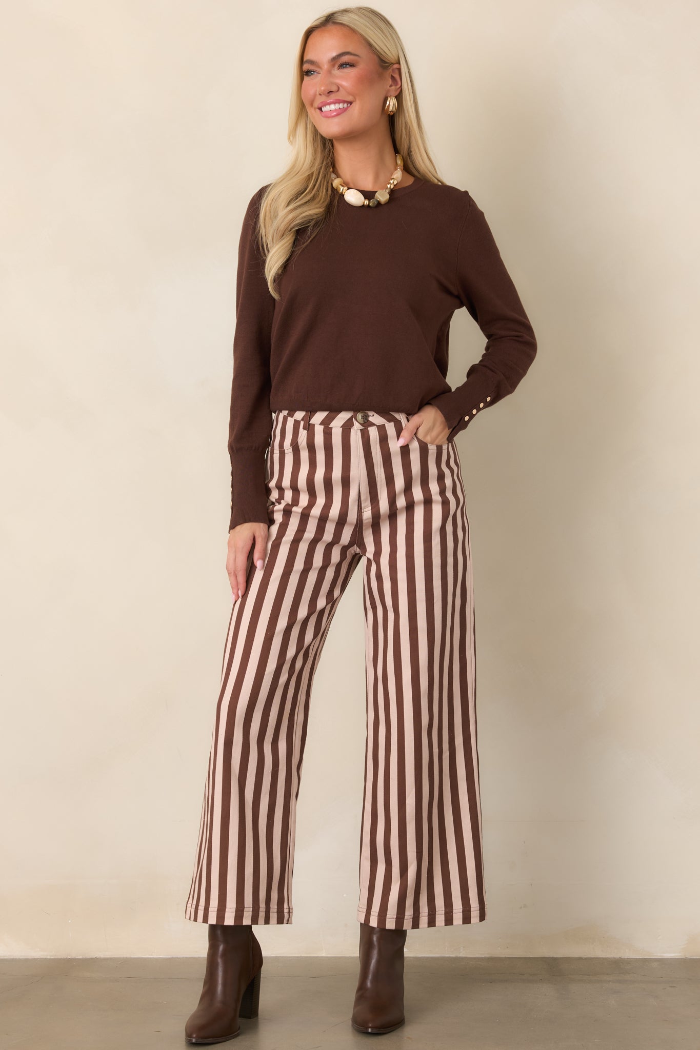 Brown and ivory vertically striped pants with a high-rise waist and cropped wide-leg silhouette, shown with front pockets and a structured fit.