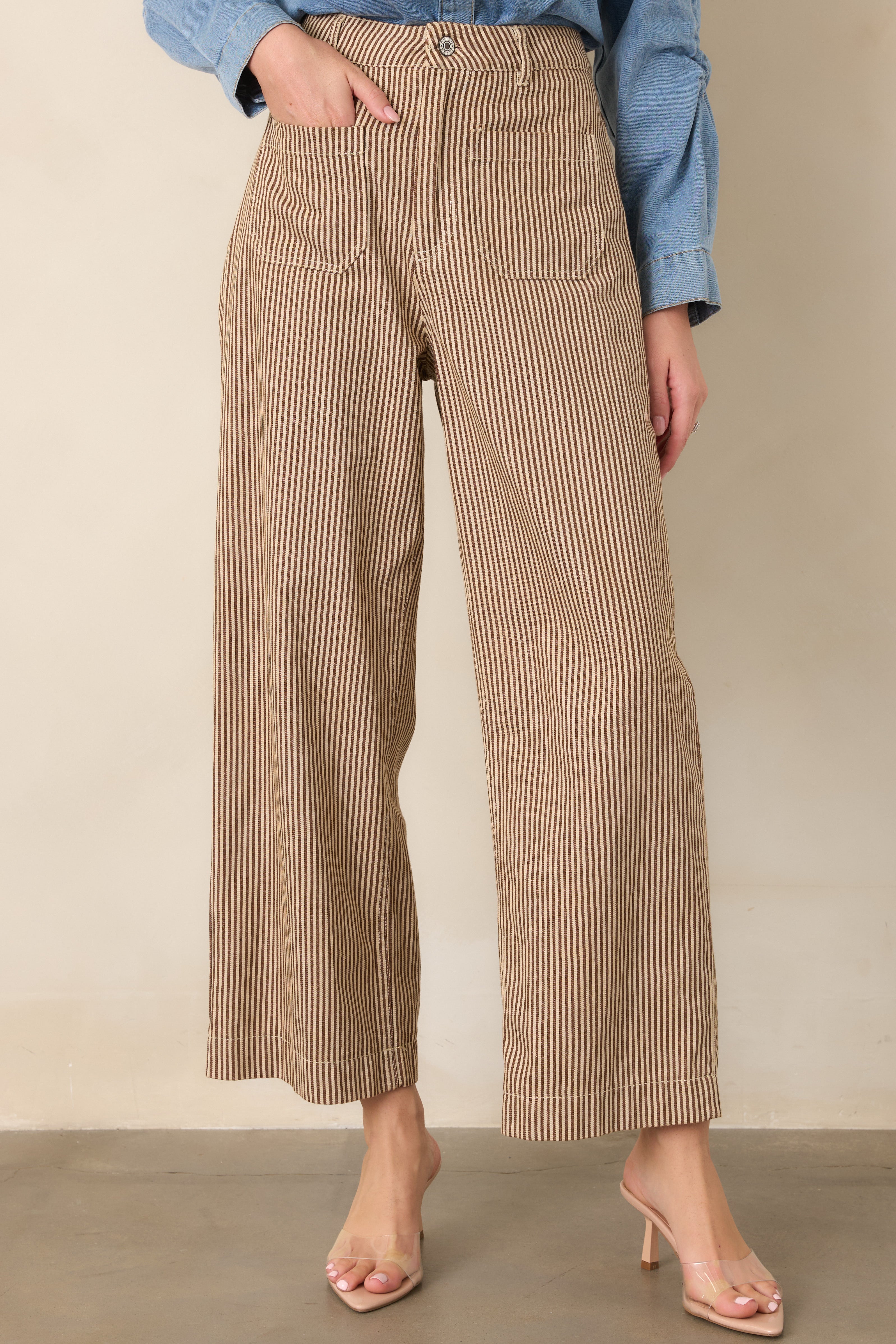 Detailed view of the vertical brown and ivory stripe pattern across the high-rise waist and relaxed upper leg of the pants.