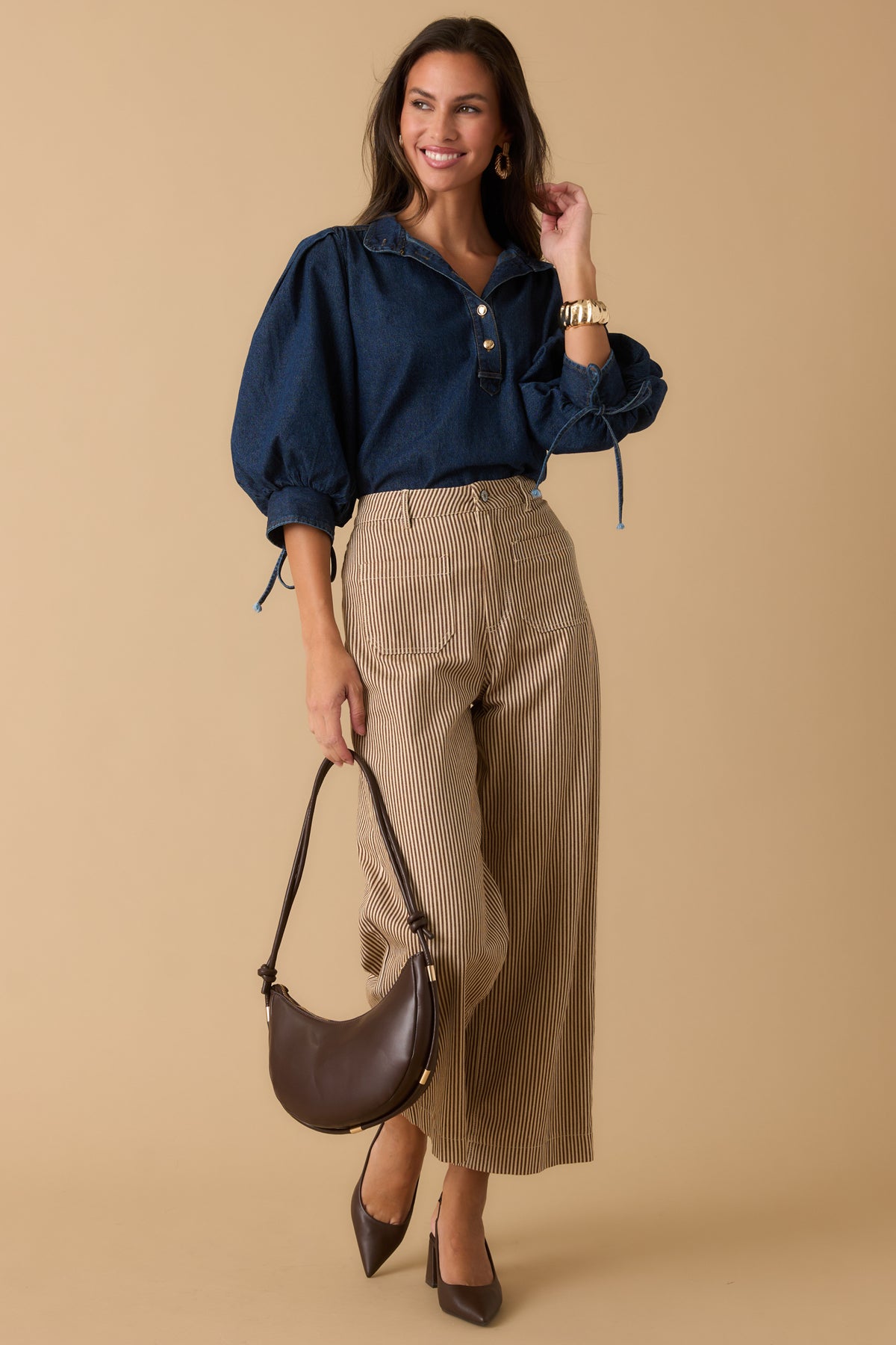Brown and ivory striped pants featuring a high-rise waist, patch pockets, button-and-zip closure, and relaxed wide-leg silhouette.