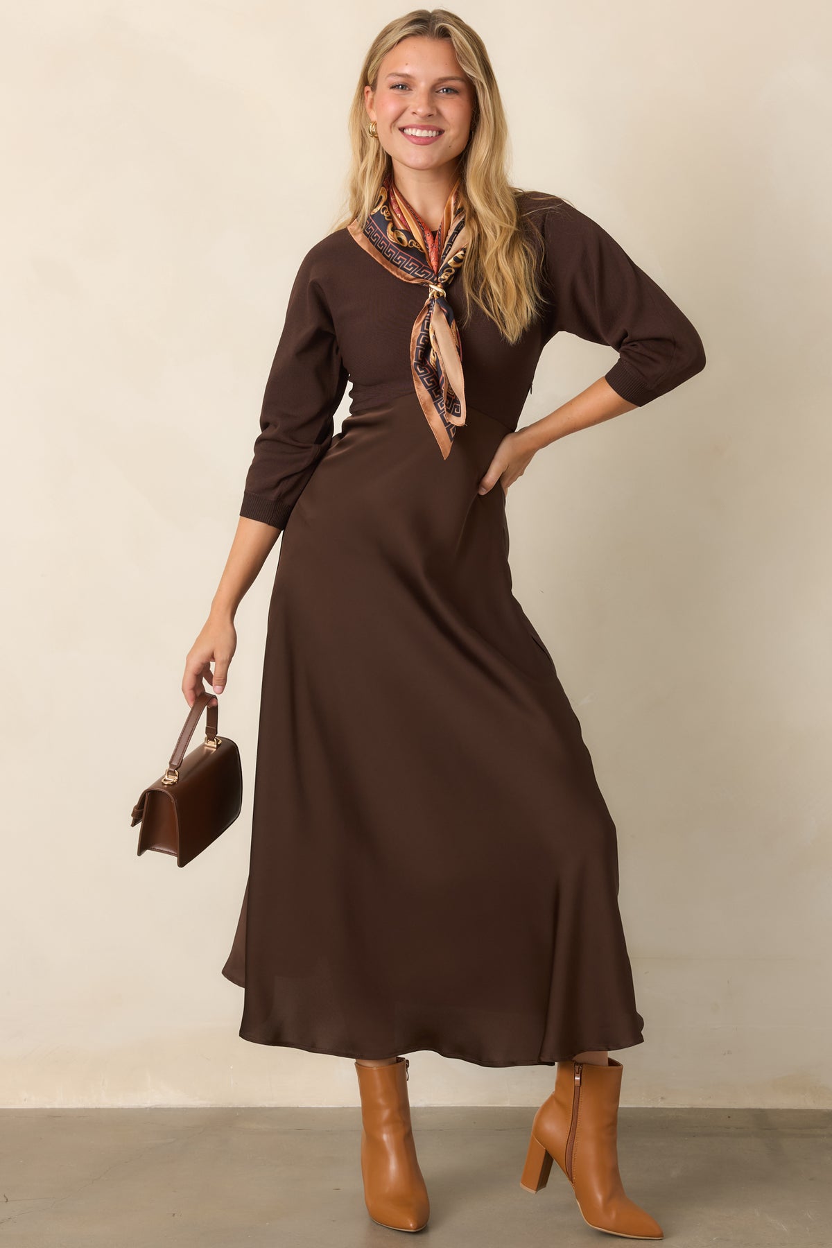Two-tone brown midi dress combining a fitted knit bodice with three-quarter sleeves and a softly flowing satin skirt.