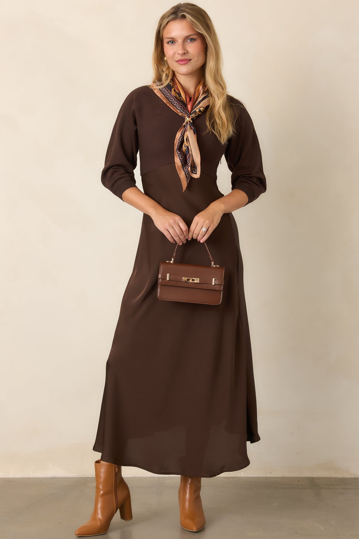 Brown knit midi dress featuring a fitted bodice, classic round neckline, three-quarter sleeves, and a high-waisted satin A-line skirt.