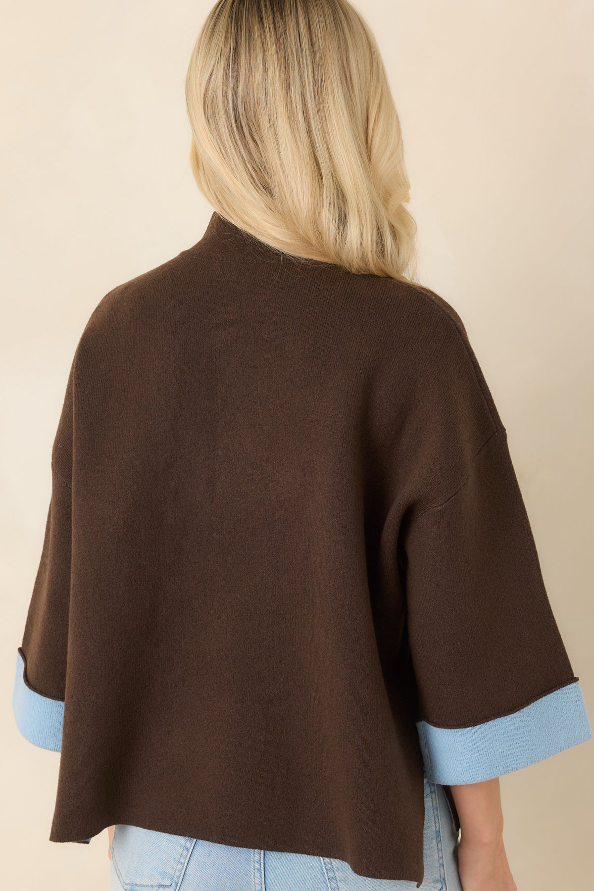 Rear of the brown knit top showing its relaxed boxy silhouette, dropped shoulders, and wide three-quarter sleeves.