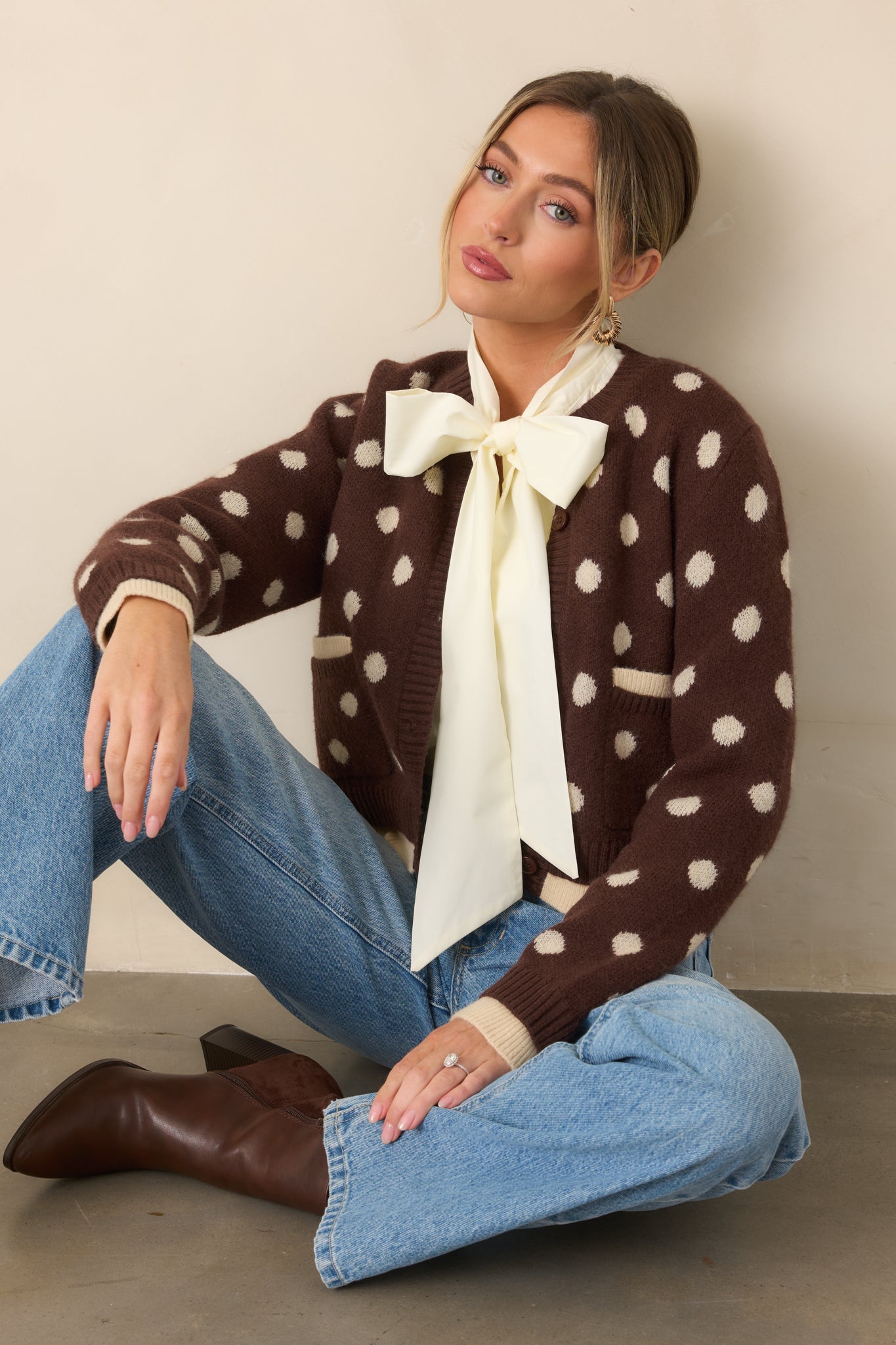 Relaxed brown knit cardigan featuring ivory polka dots, contrasting trim beneath the ribbed hem and cuffs, and front patch pockets.
