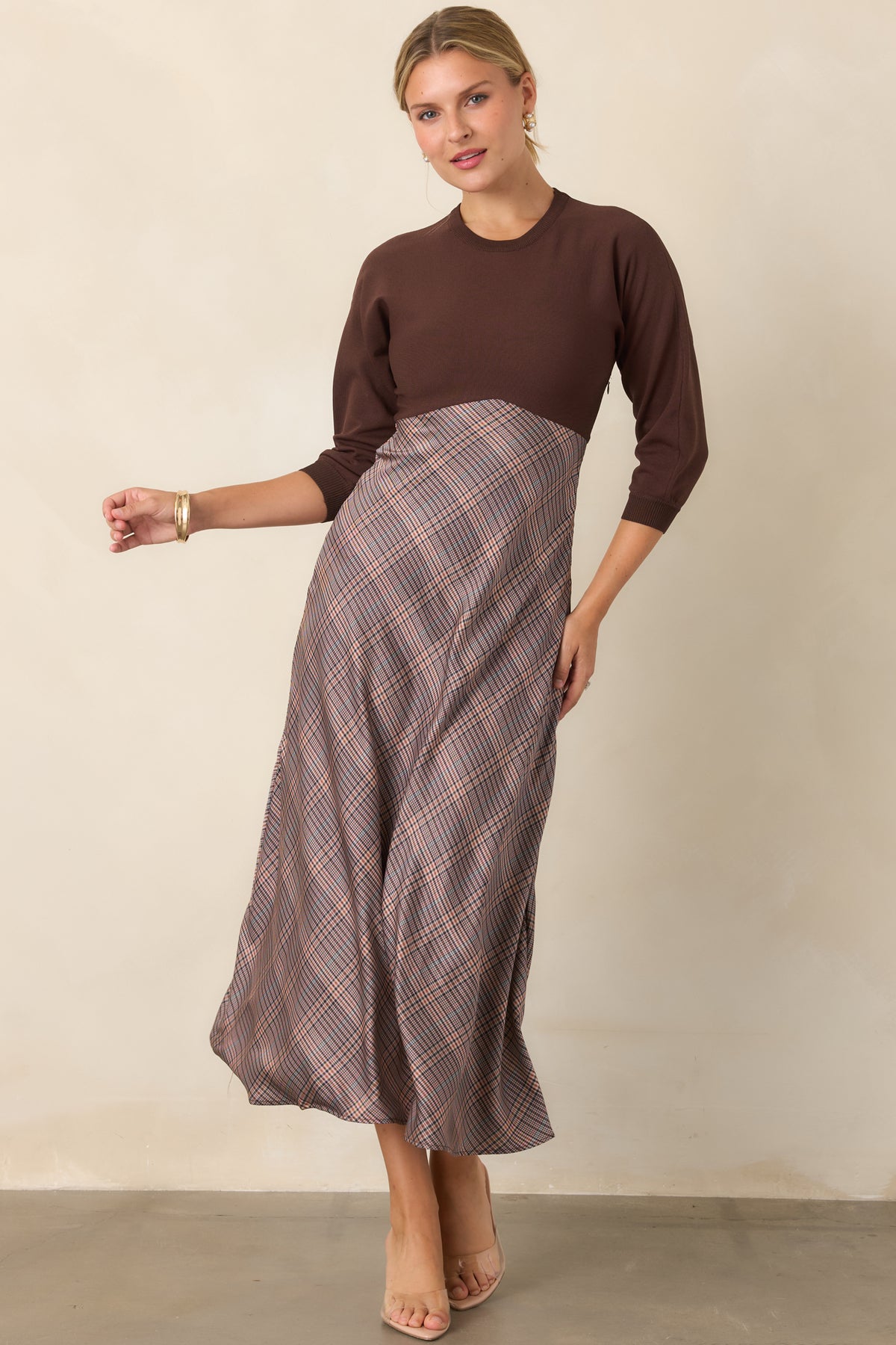Brown knit dress featuring a close-fitting bodice, rounded neckline, and relaxed three-quarter sleeves.