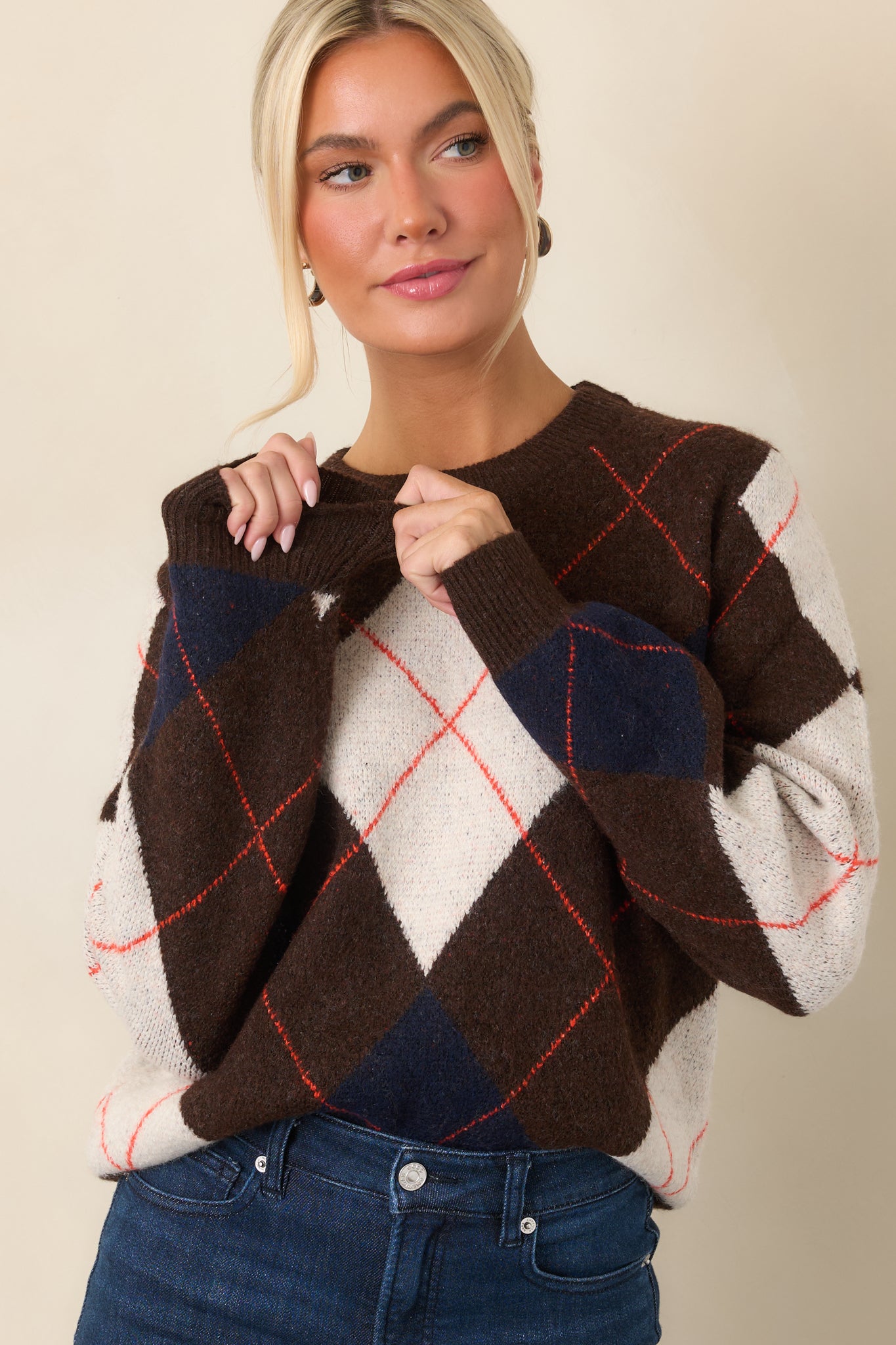 Brown knit fabric highlights ivory and navy diamond motifs interspersed with delicate rust-red lines.