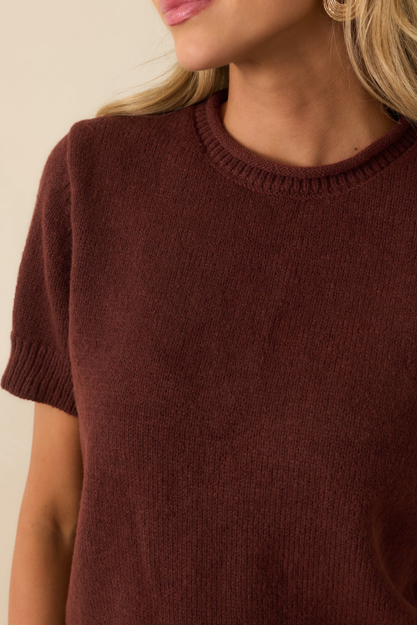 Detailed shot of brown knit texture and rolled hem finishing.