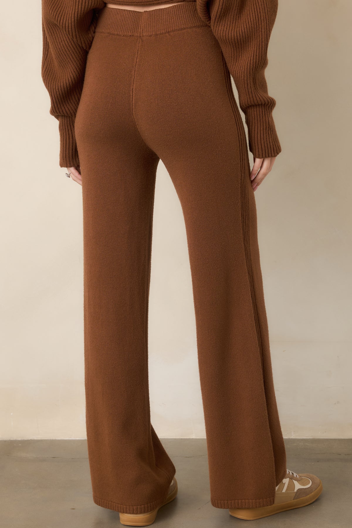 Rear view of the brown knit pants showcasing the high-rise elastic waistband, smooth fit through the hips, clean seams, and flowing wide-leg silhouette.