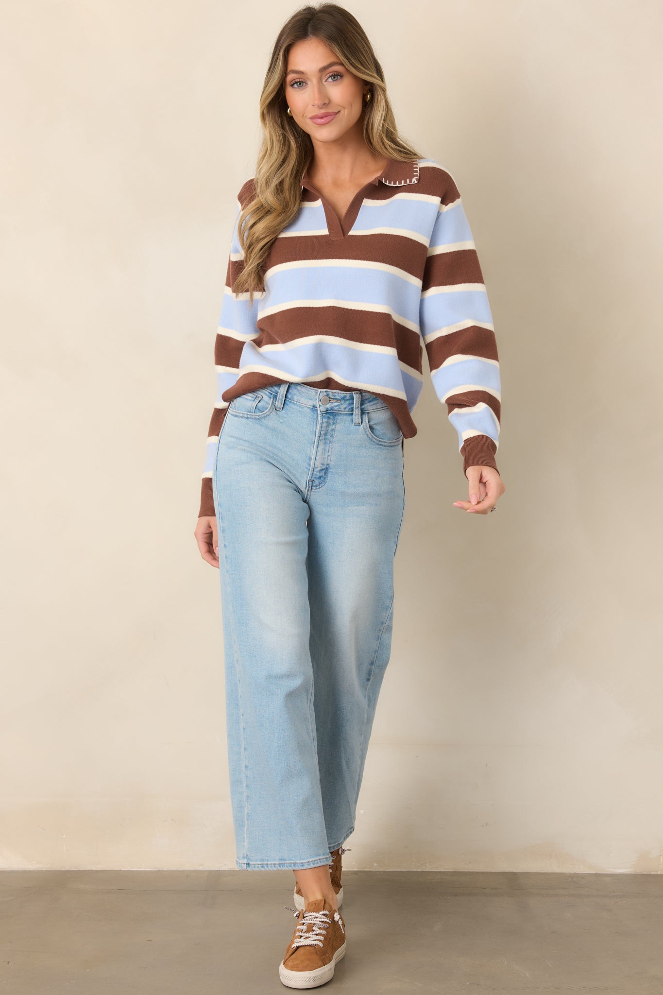 Striped knit top combining rich brown, pale blue, and white horizontal panels with decorative collar stitching, long sleeves, and softly fitted ribbed cuffs.