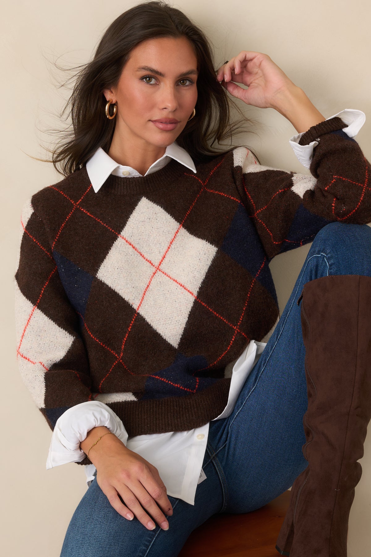 Brown long-sleeve knit top displaying repeating ivory and navy diamond shapes with rust-red accents and a classic ribbed crew neckline.