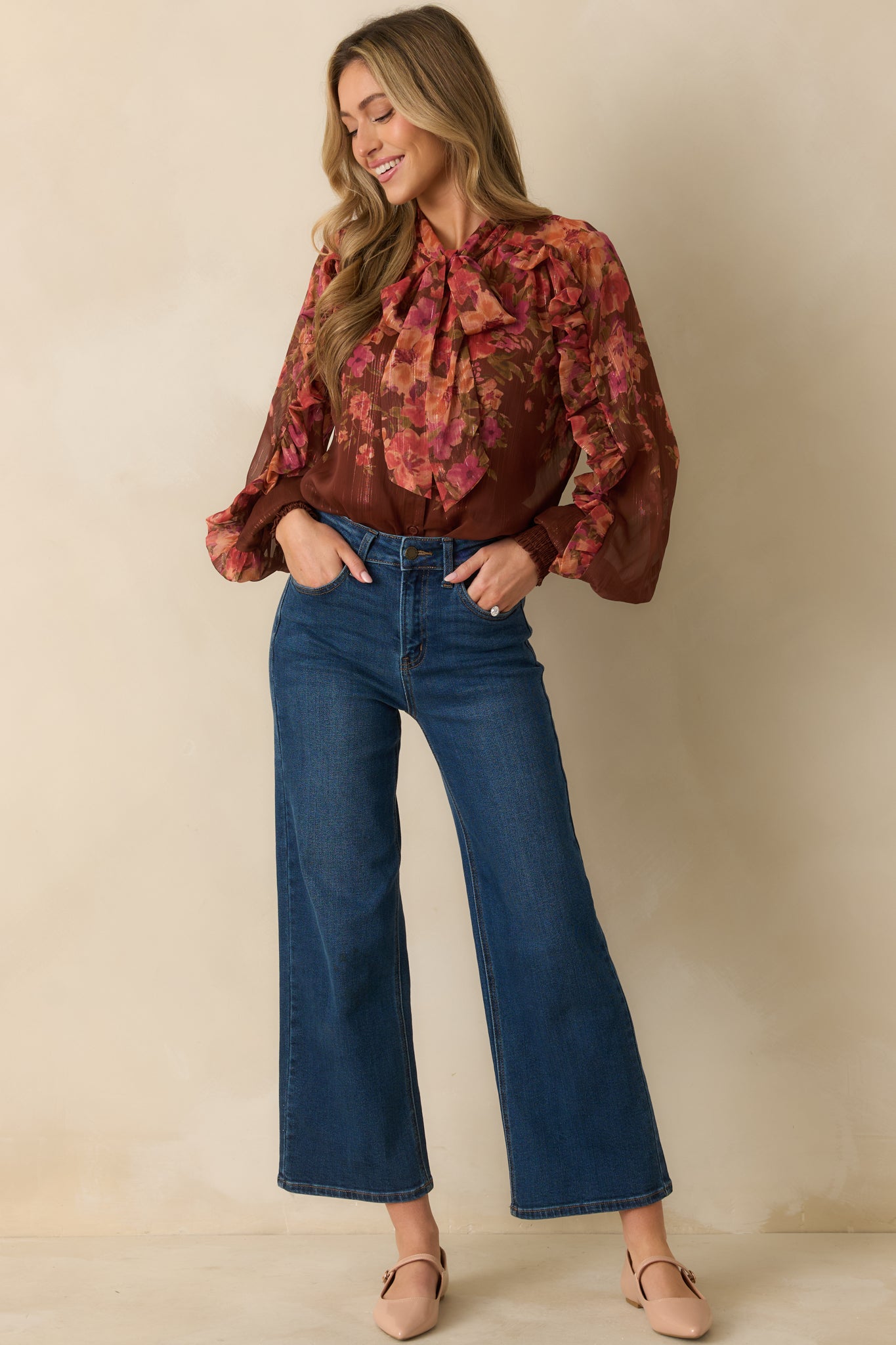Brown multi floral print blouse with self-tie neckline, long blouson sleeves, and ruffle detailing along the front.
