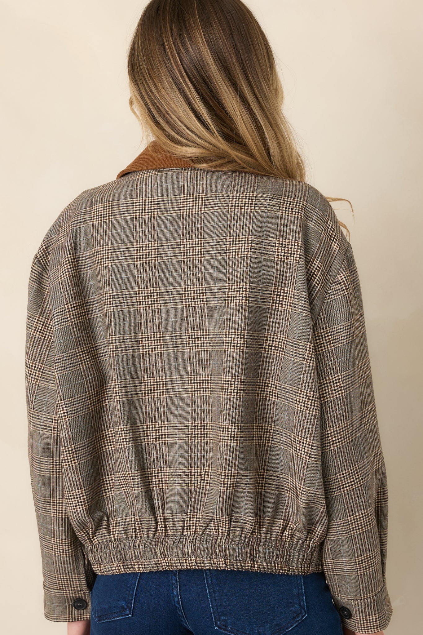 Rear view of the brown multi-plaid bomber jacket showing its woven plaid pattern, relaxed shape, and elasticized hem.