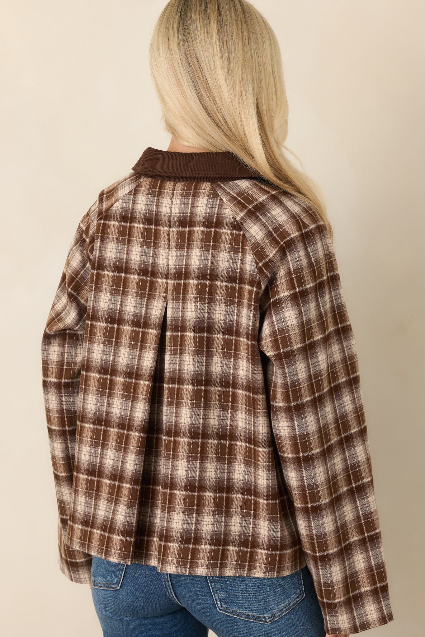 Rear view of the brown plaid jacket showing the center-back pleat, boxy silhouette, long sleeves, and relaxed fit.
