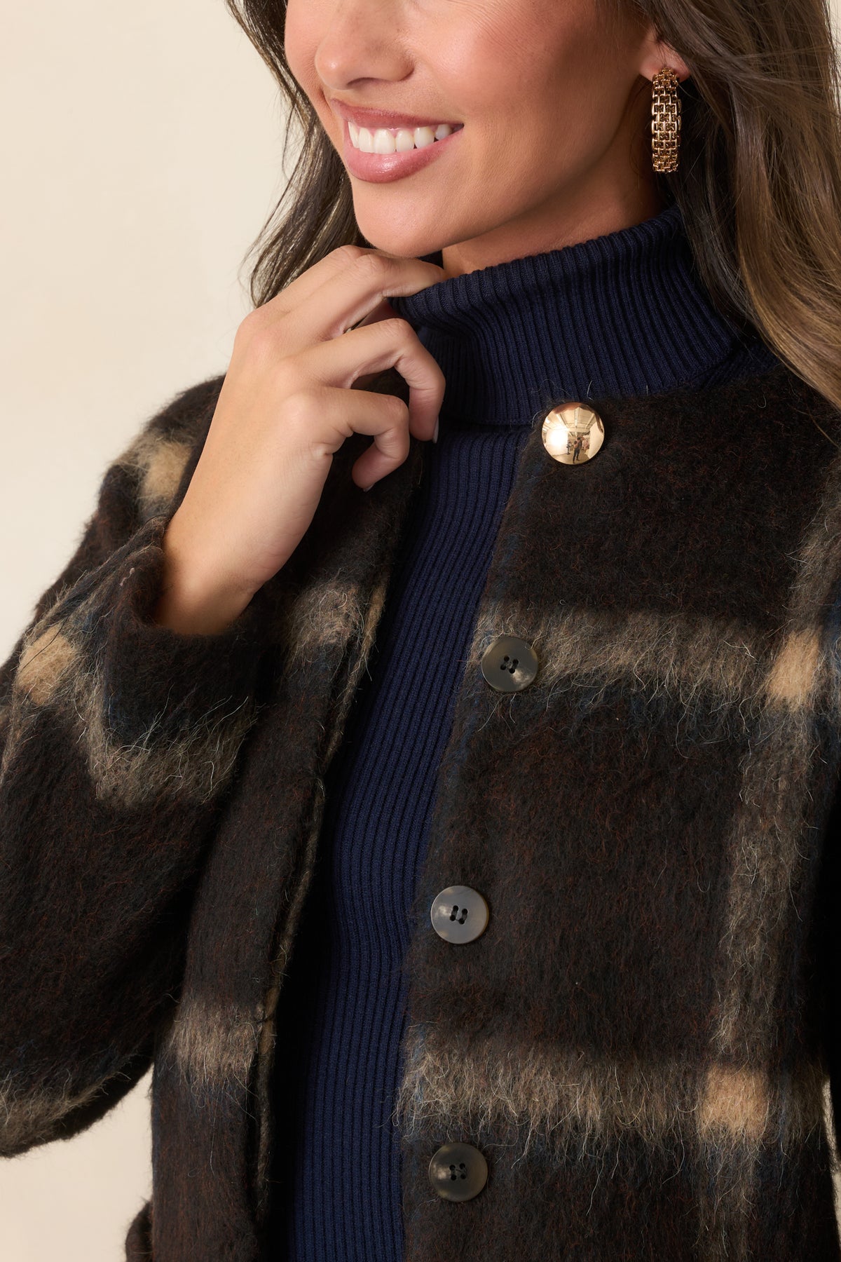Close-up of the tan and navy plaid, gold-tone top button, and concealed button-front detailing.