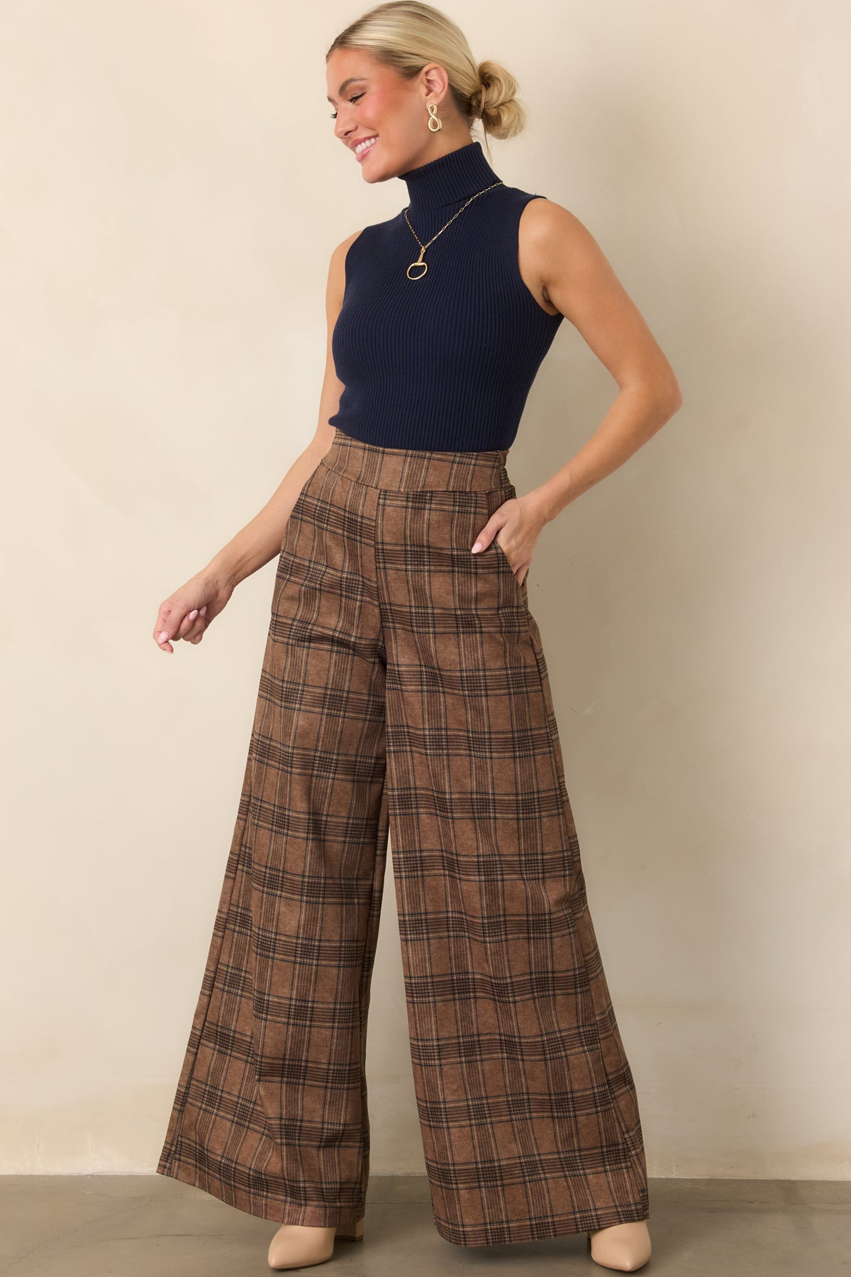 Brown plaid pants featuring a high-rise waist and long wide-leg silhouette with a smooth, softly structured drape