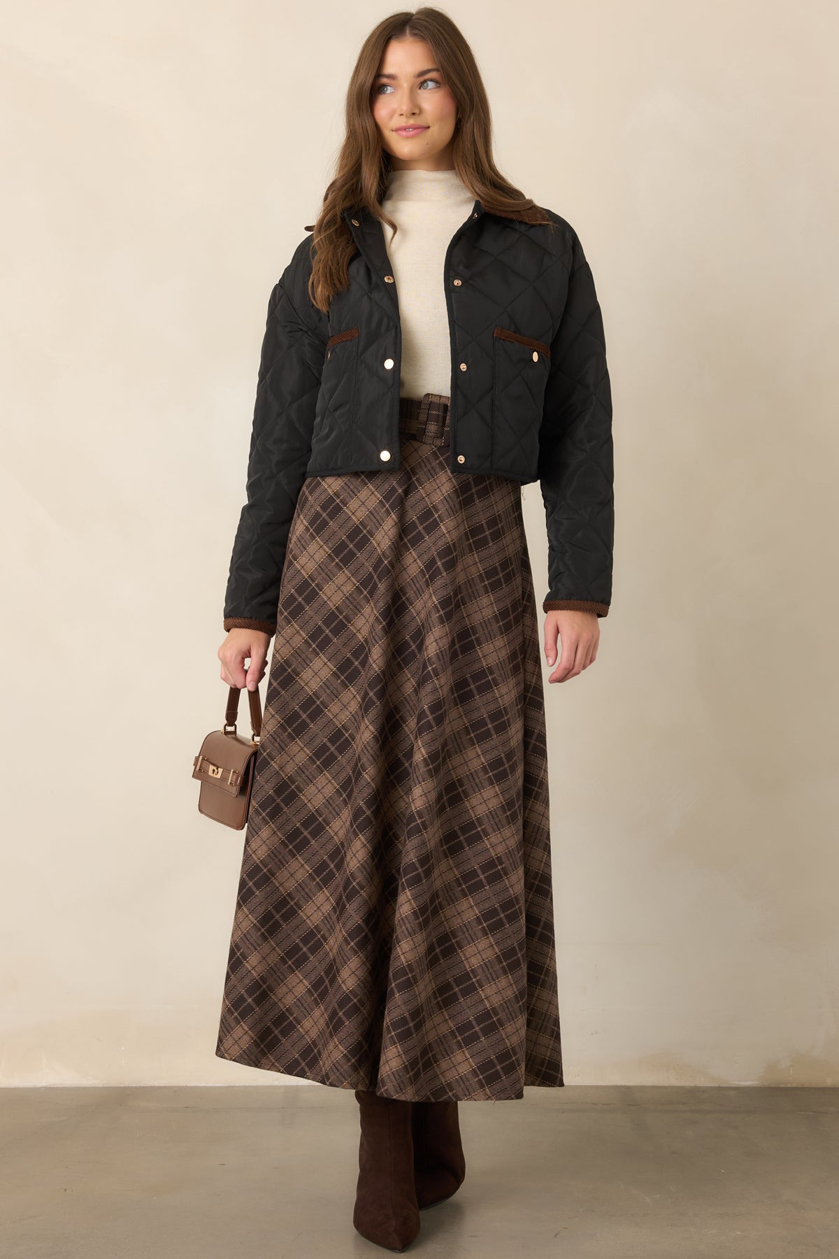Vintage-inspired plaid maxi skirt showcasing rich brown tones, a coordinating belt, and a gently sweeping silhouette.