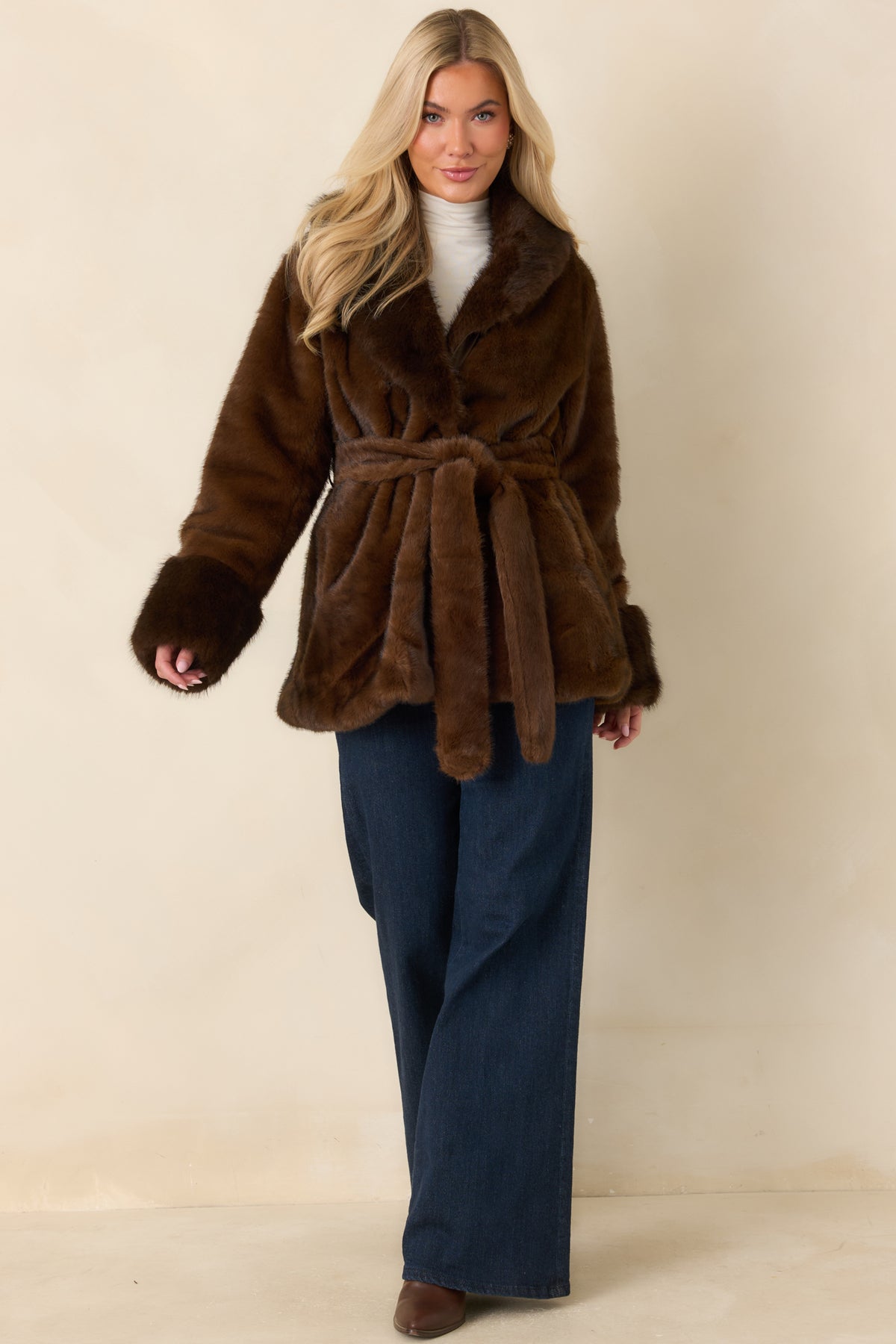 Plush brown faux fur coat featuring long sleeves, statement cuffs, and a hip-length silhouette