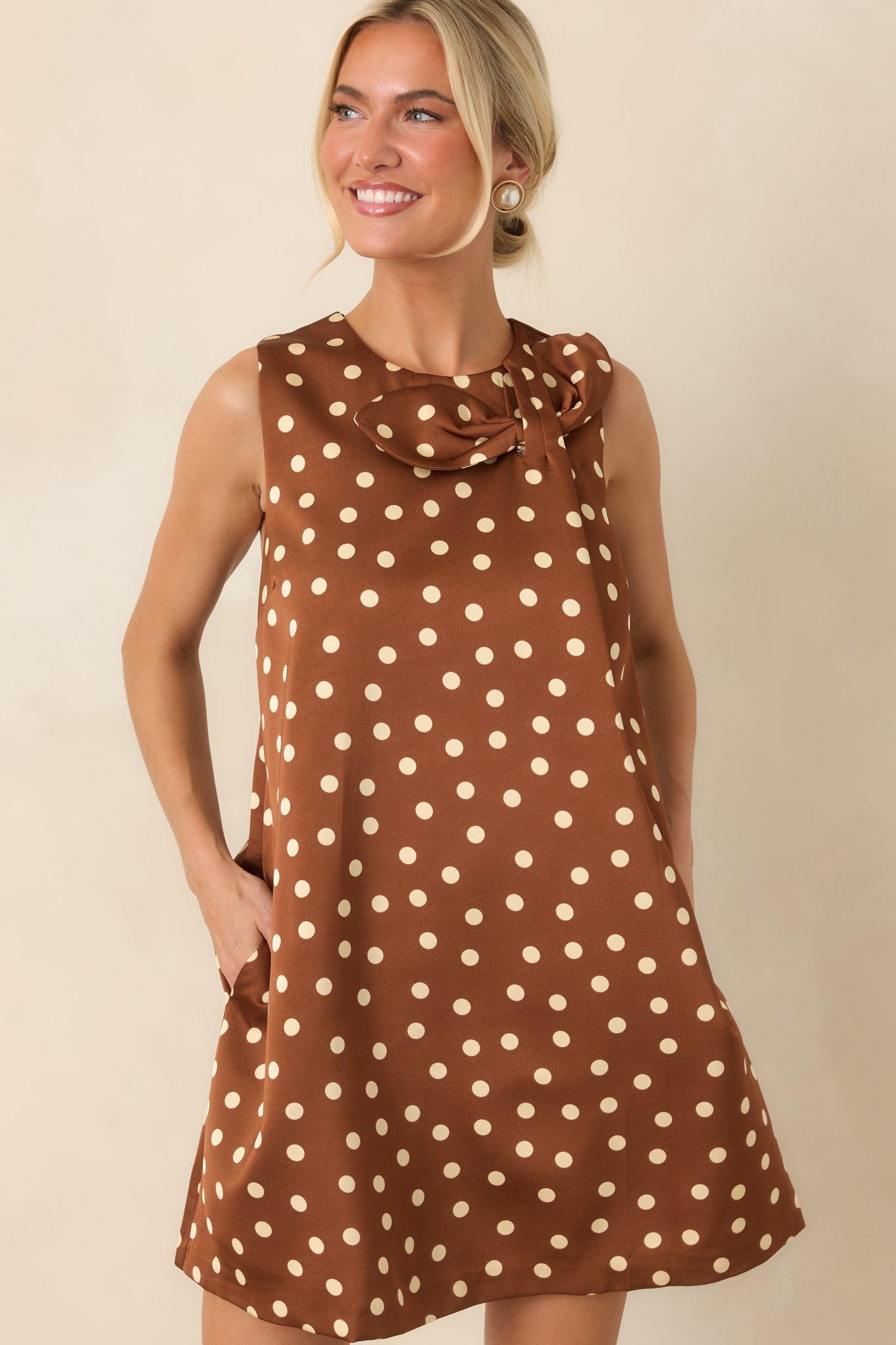 Cream polka dots contrast against the rich brown woven fabric of this sleeveless shift dress.