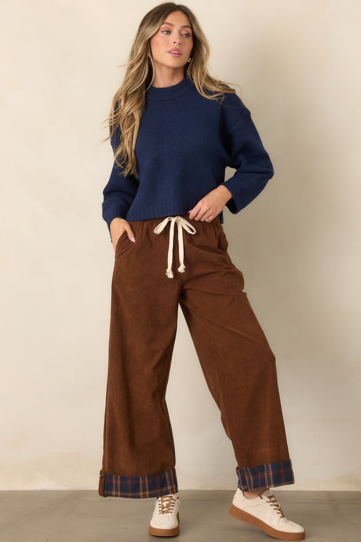 Classic brown pants with relaxed wide legs and playful navy plaid cuffs framing the cropped hem.