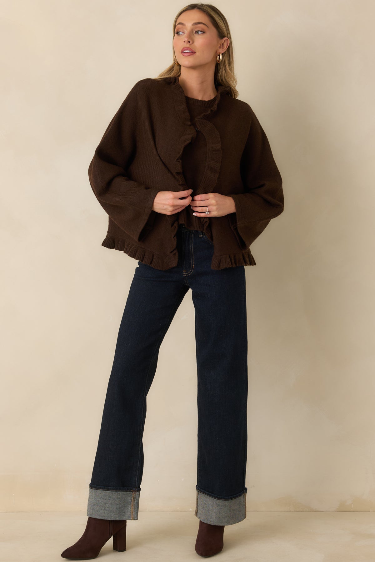 Brown knit cape cardigan with a relaxed open silhouette, wide long sleeves, and ruffle trim framing the front and hem.