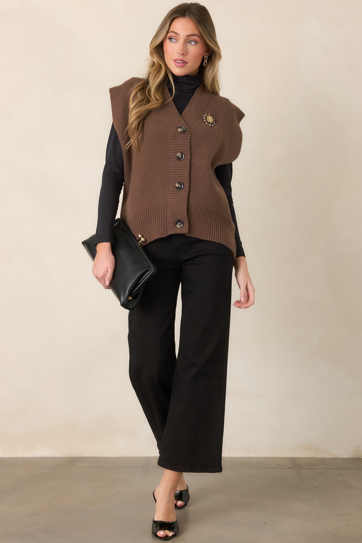 Soft brown knit vest with a relaxed silhouette, extended shoulders, and a button-front design framed by wide ribbed edges.