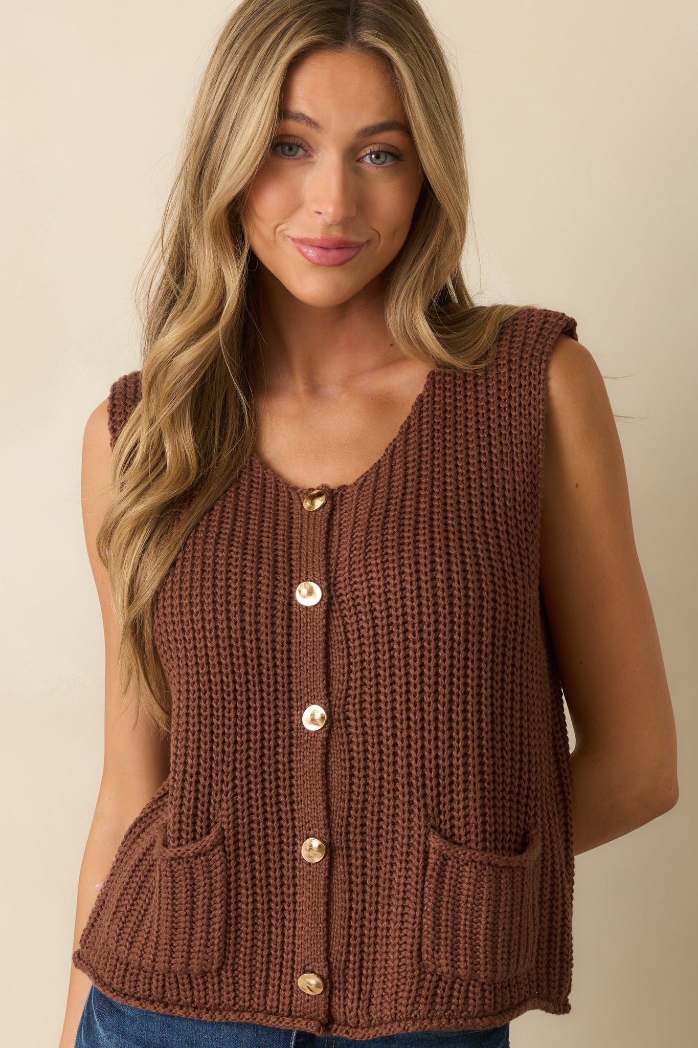 Cropped image focusing on the scoop neckline and upper ribbed knit detailing of the brown sweater vest.