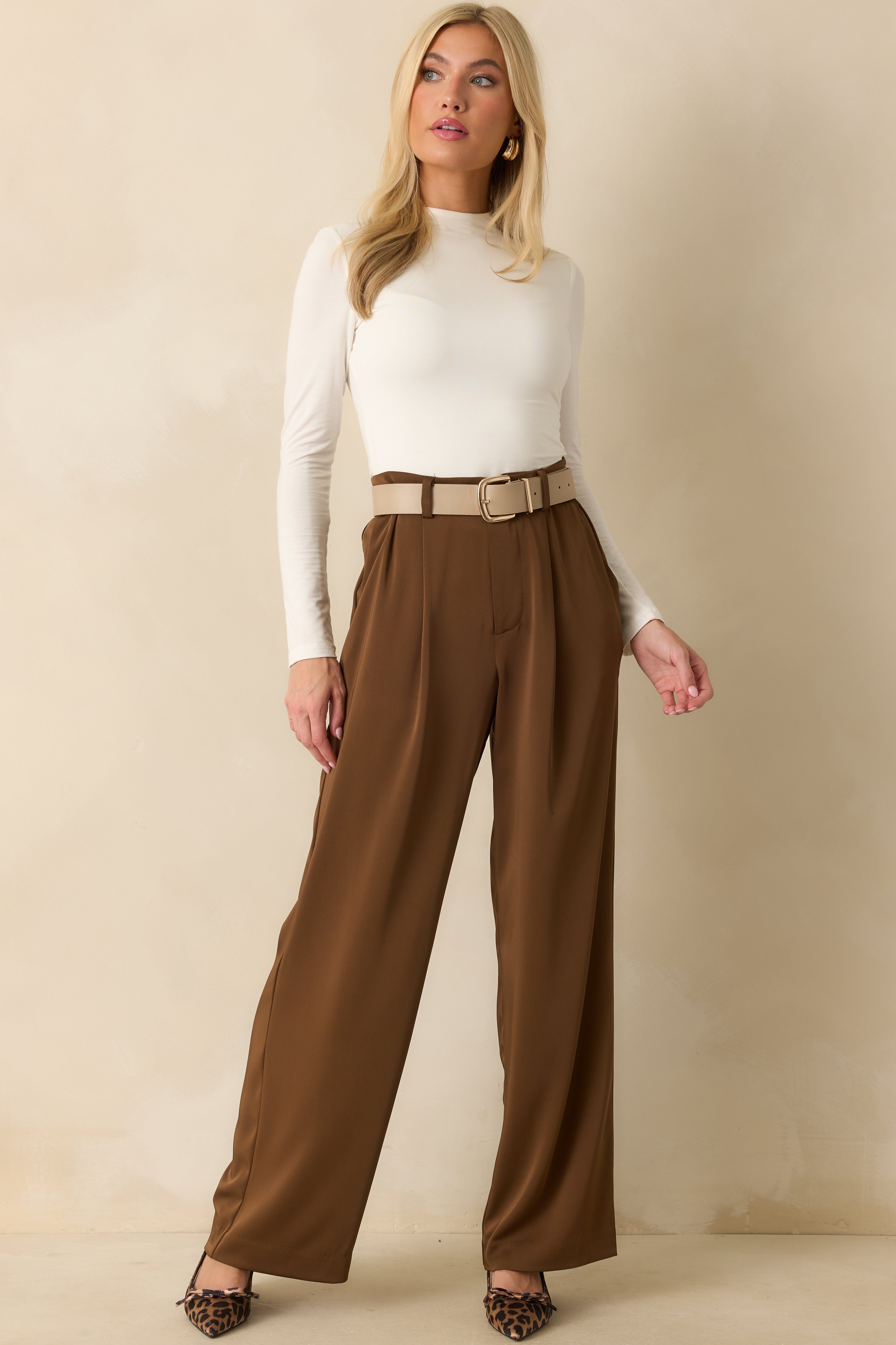 Front view of brown trousers showing the high-rise waist, front pleats, and wide-leg silhouette.