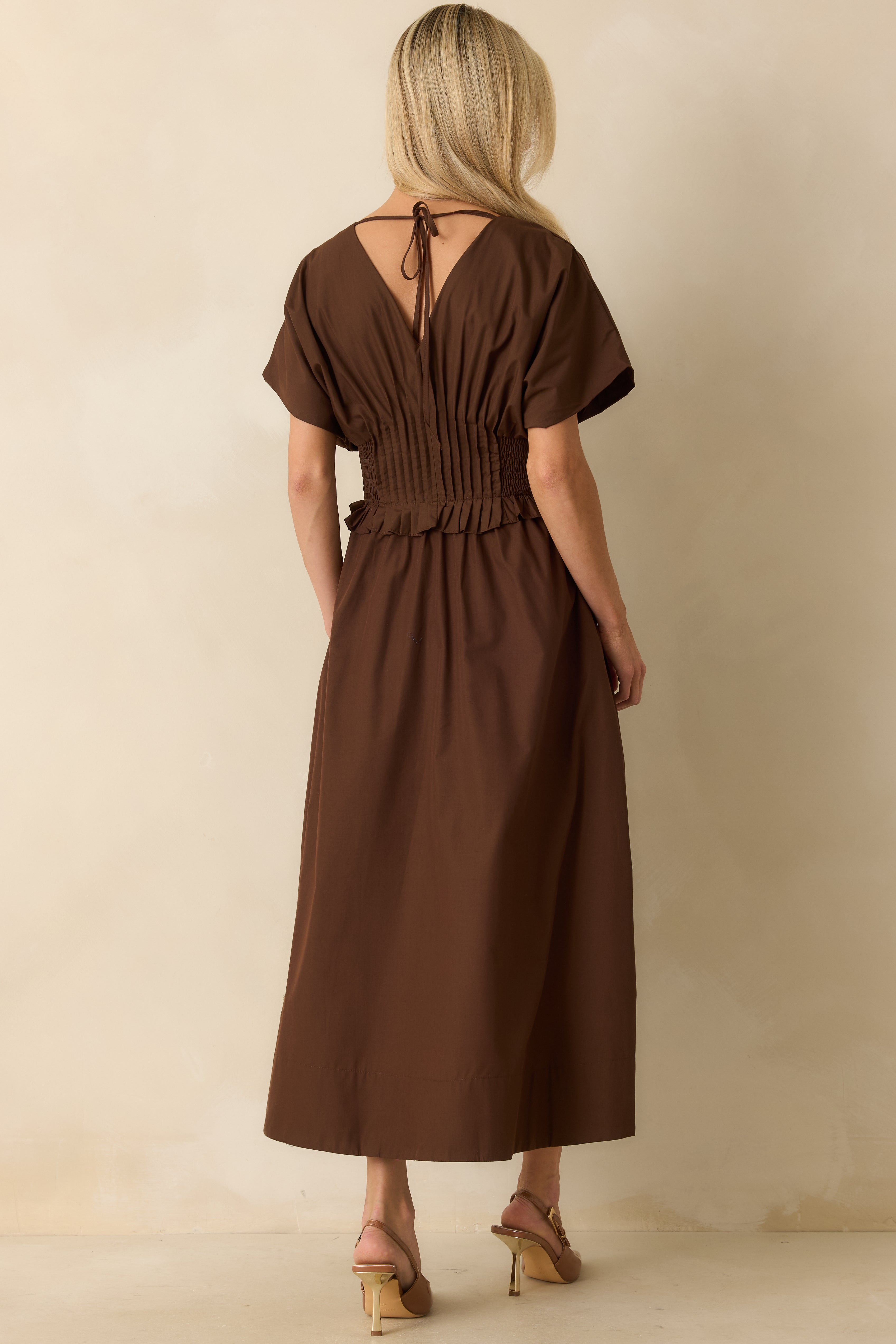 Rear view of the brown woven maxi dress highlighting the wide smocked waistband and gentle flow of the A-line skirt.
