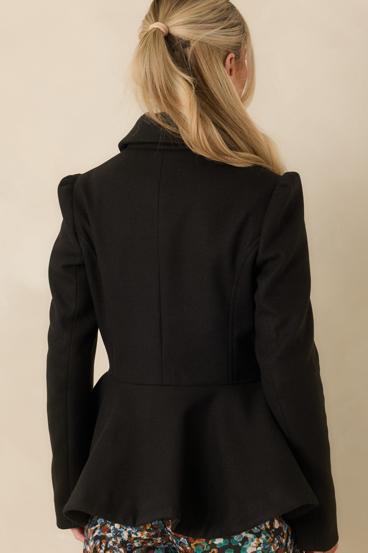 Brushed felt jacket showcasing the curved seams, fitted waist, and sculptural peplum hem from the rear.