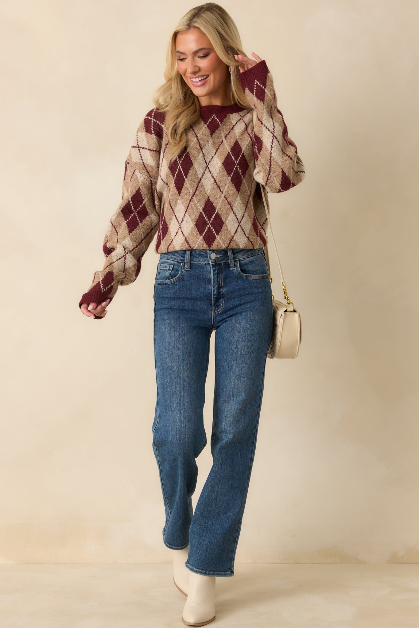 Burgundy argyle knit sweater showing relaxed fit with ribbed cuffs and hem.