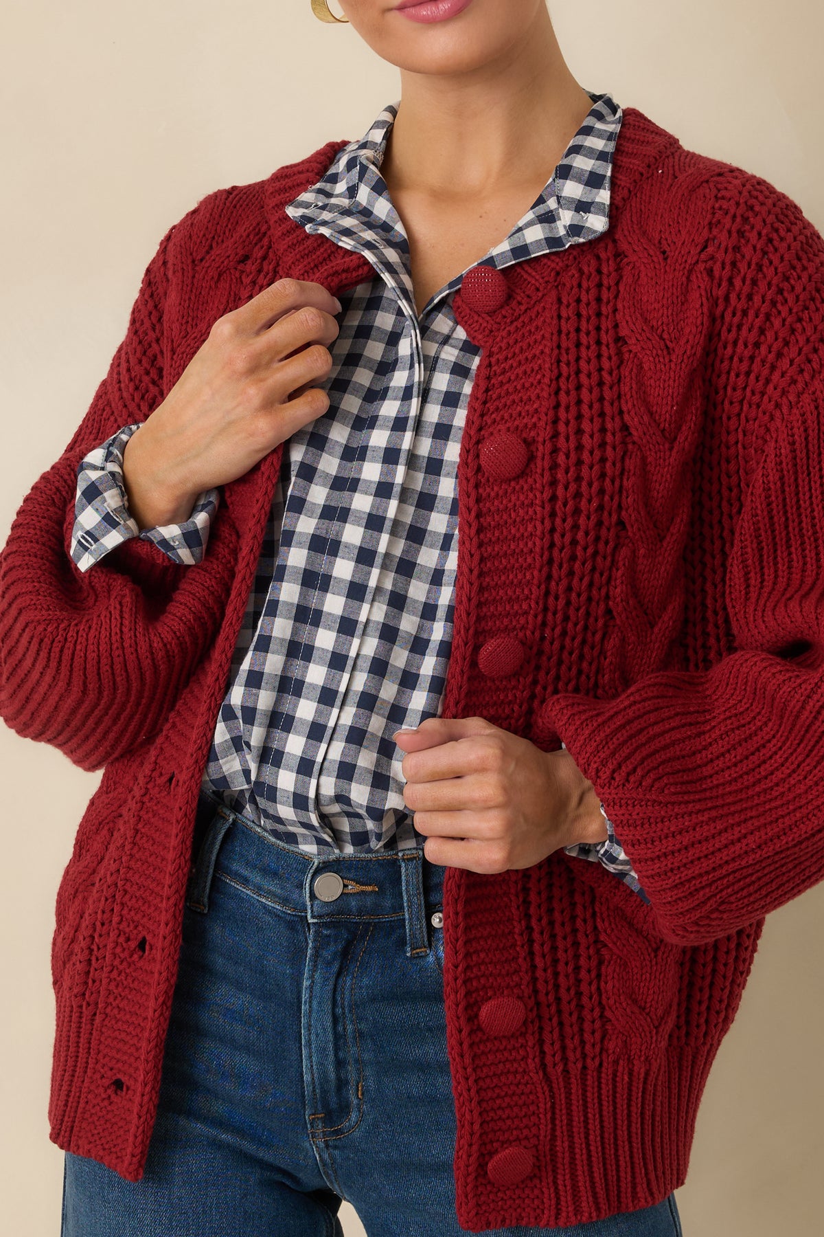 Burgundy cardigan close-up highlighting the chunky cable-knit pattern and tonal knit-covered button detailing.