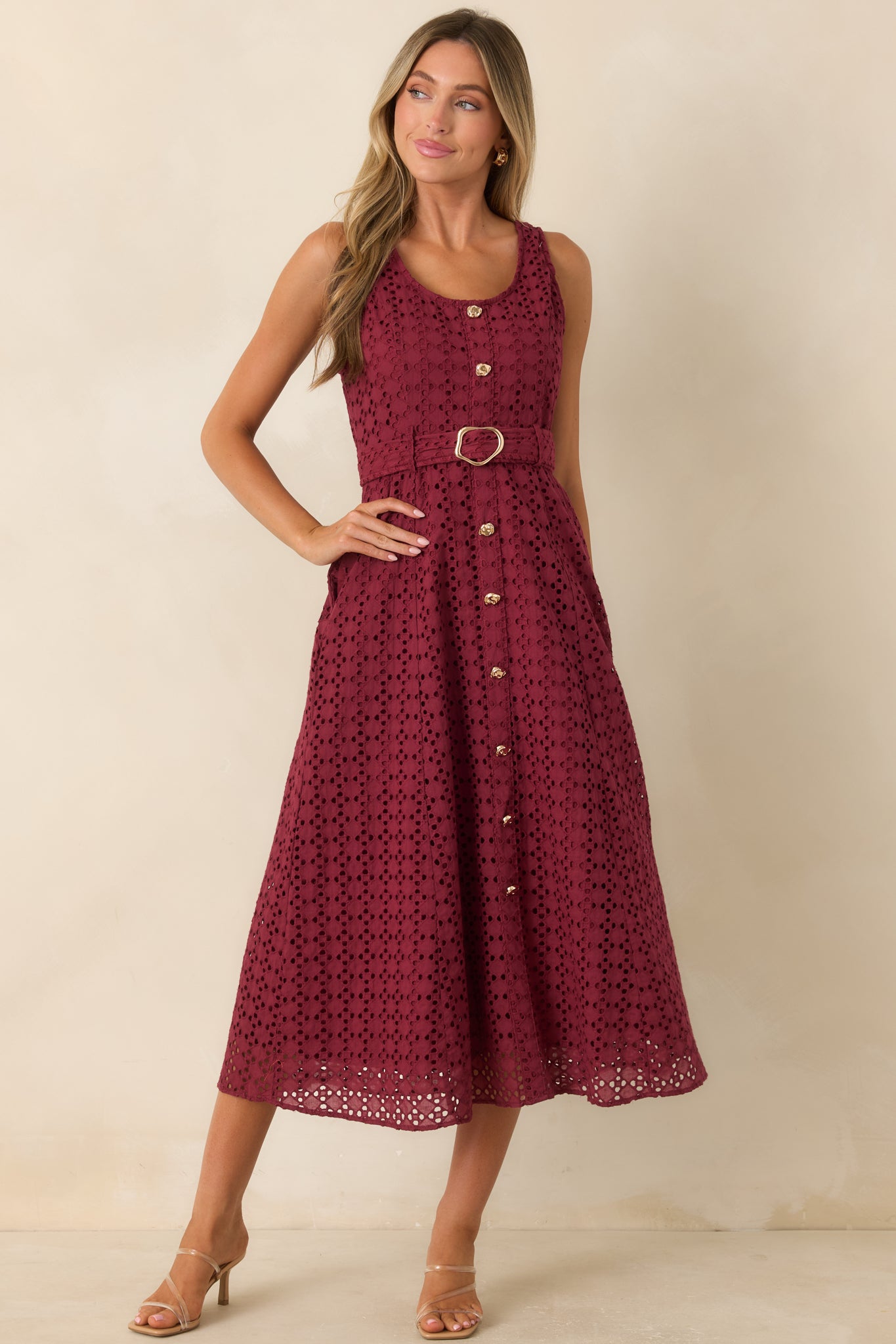 Burgundy cotton eyelet midi dress featuring a sleeveless silhouette, removable waist belt, faux button front, and side pockets.