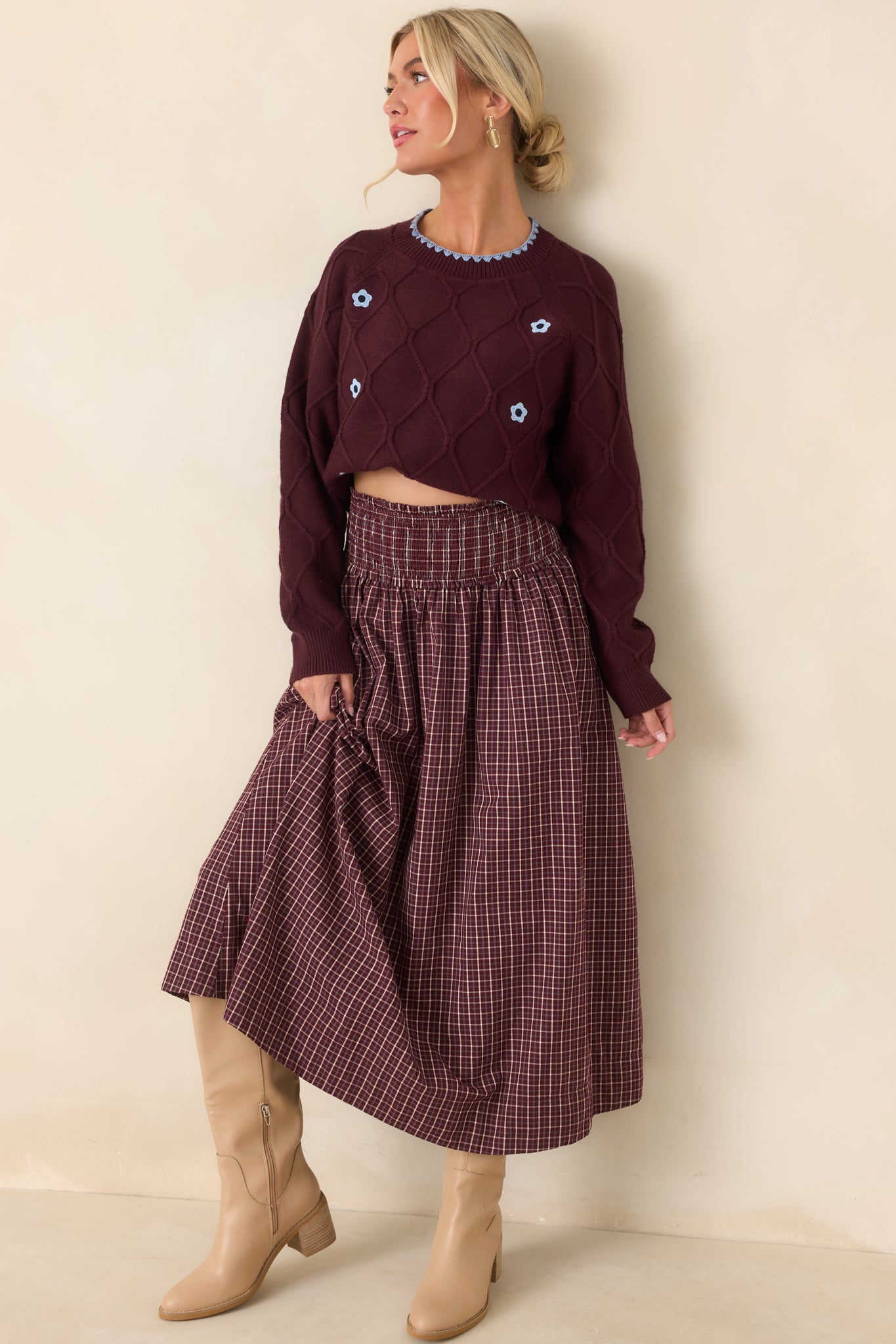 Relaxed burgundy crewneck sweater showcasing a dimensional diamond-knit texture, light blue floral accents, long sleeves, and a slightly cropped hem.