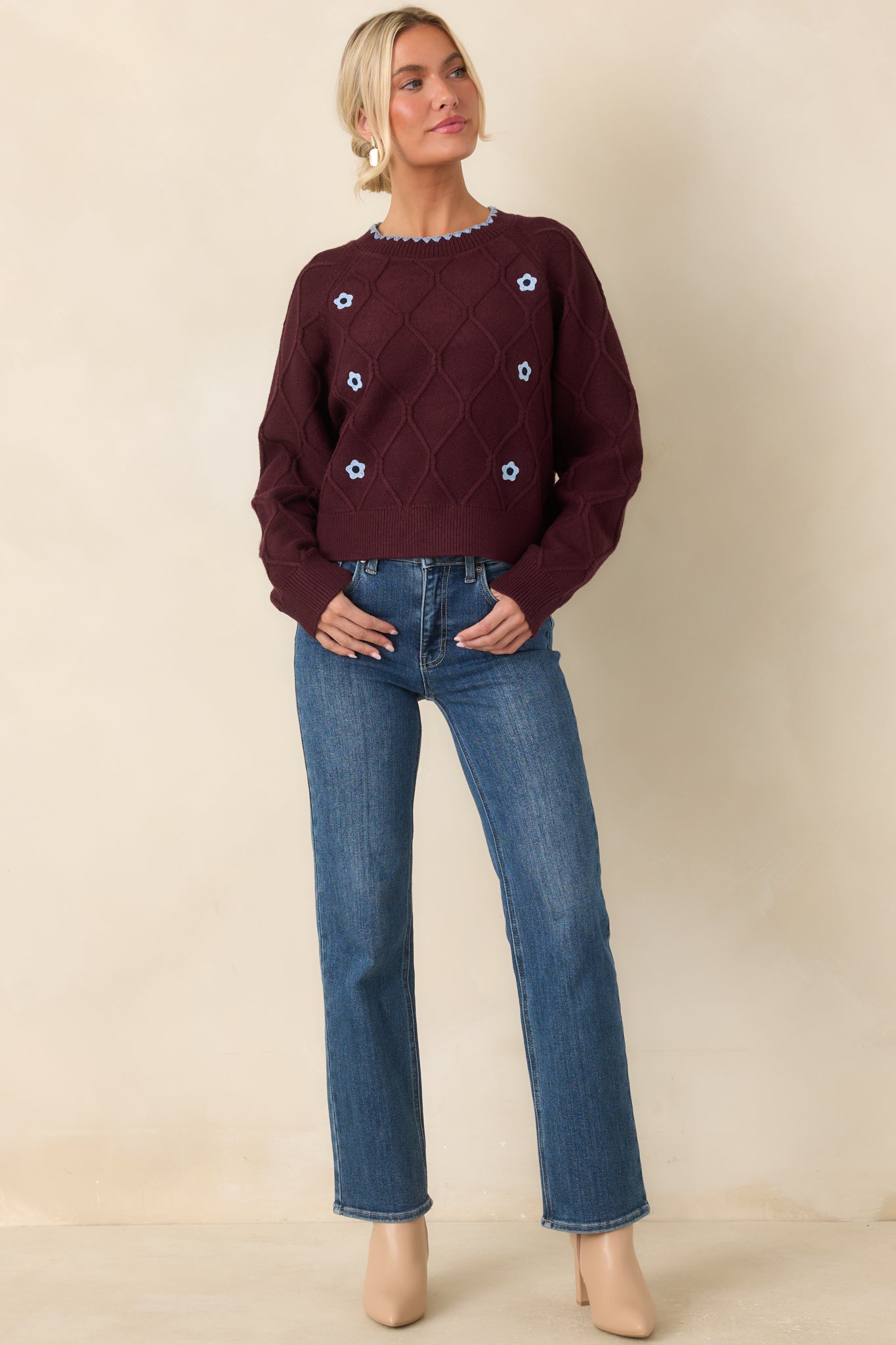 Burgundy diamond-knit sweater featuring a raised textured pattern, light blue floral accents, scalloped crew neckline trim, long sleeves, and ribbed finishes.