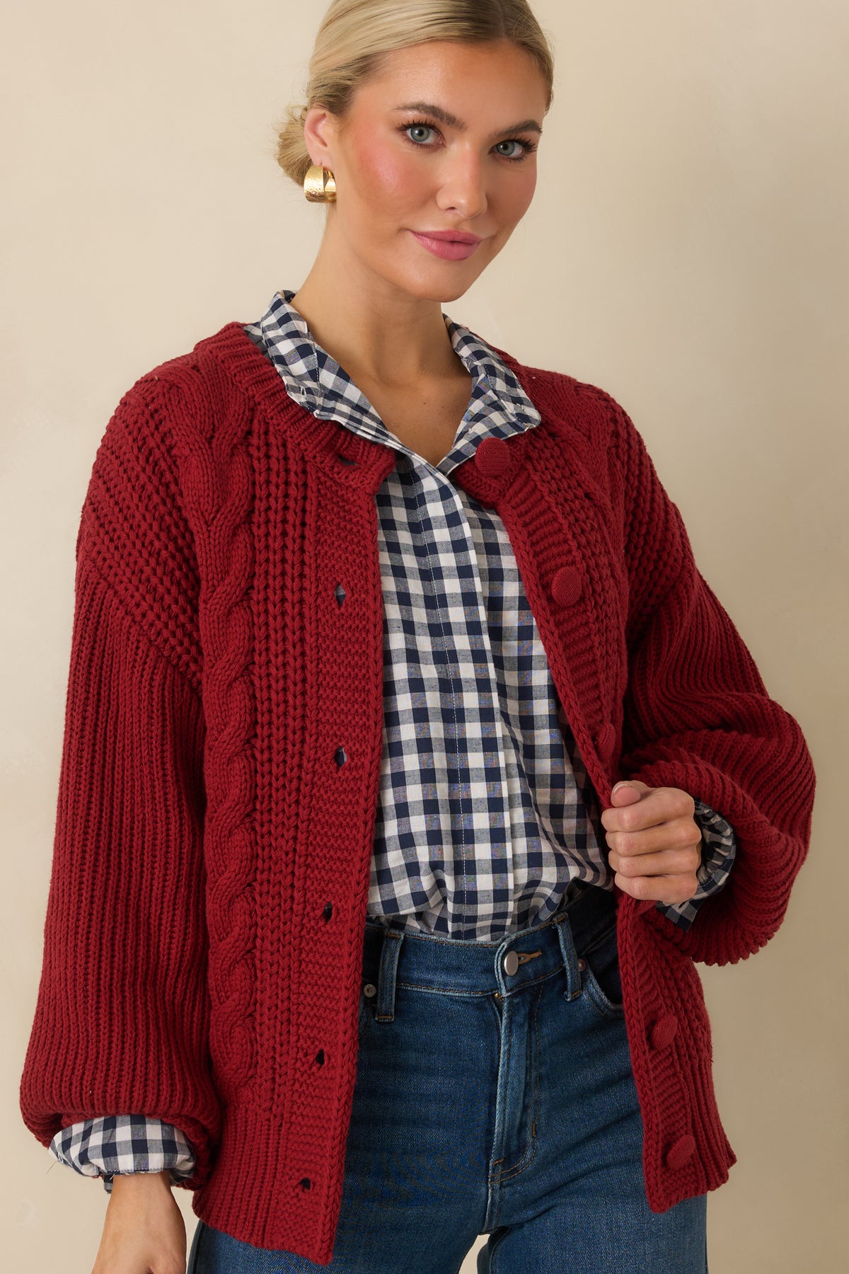 Rich burgundy cardigan combining dimensional cable-knit detailing with soft ribbed texture.