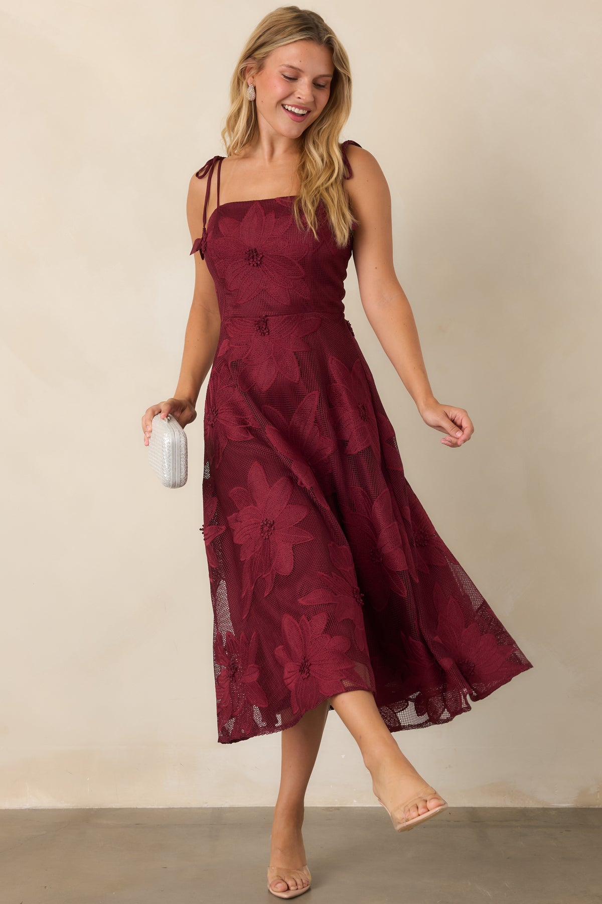Deep burgundy lace dress showcasing its textured floral pattern and flowing A-line silhouette.