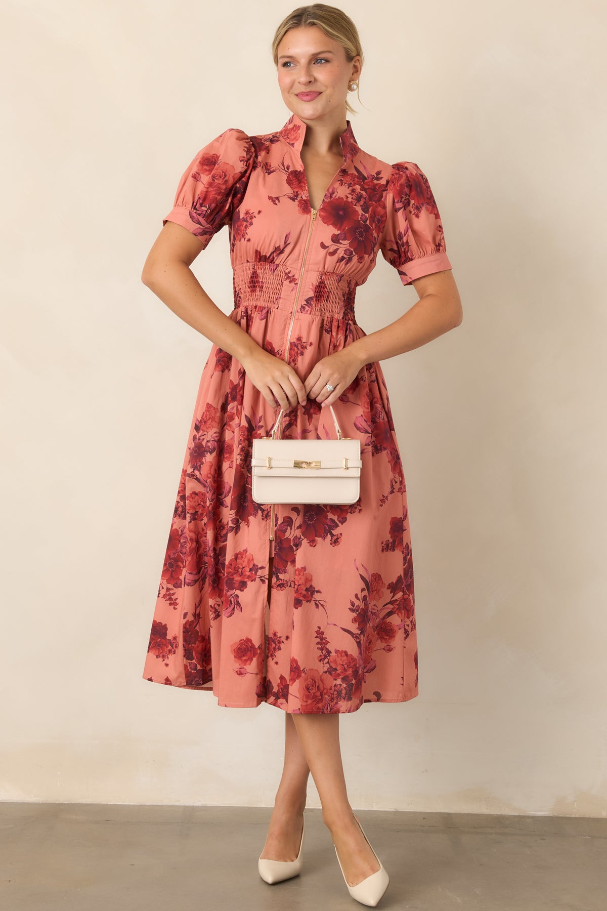 Burgundy floral midi dress featuring a warm coral backdrop, structured stand collar, and short puff sleeves.