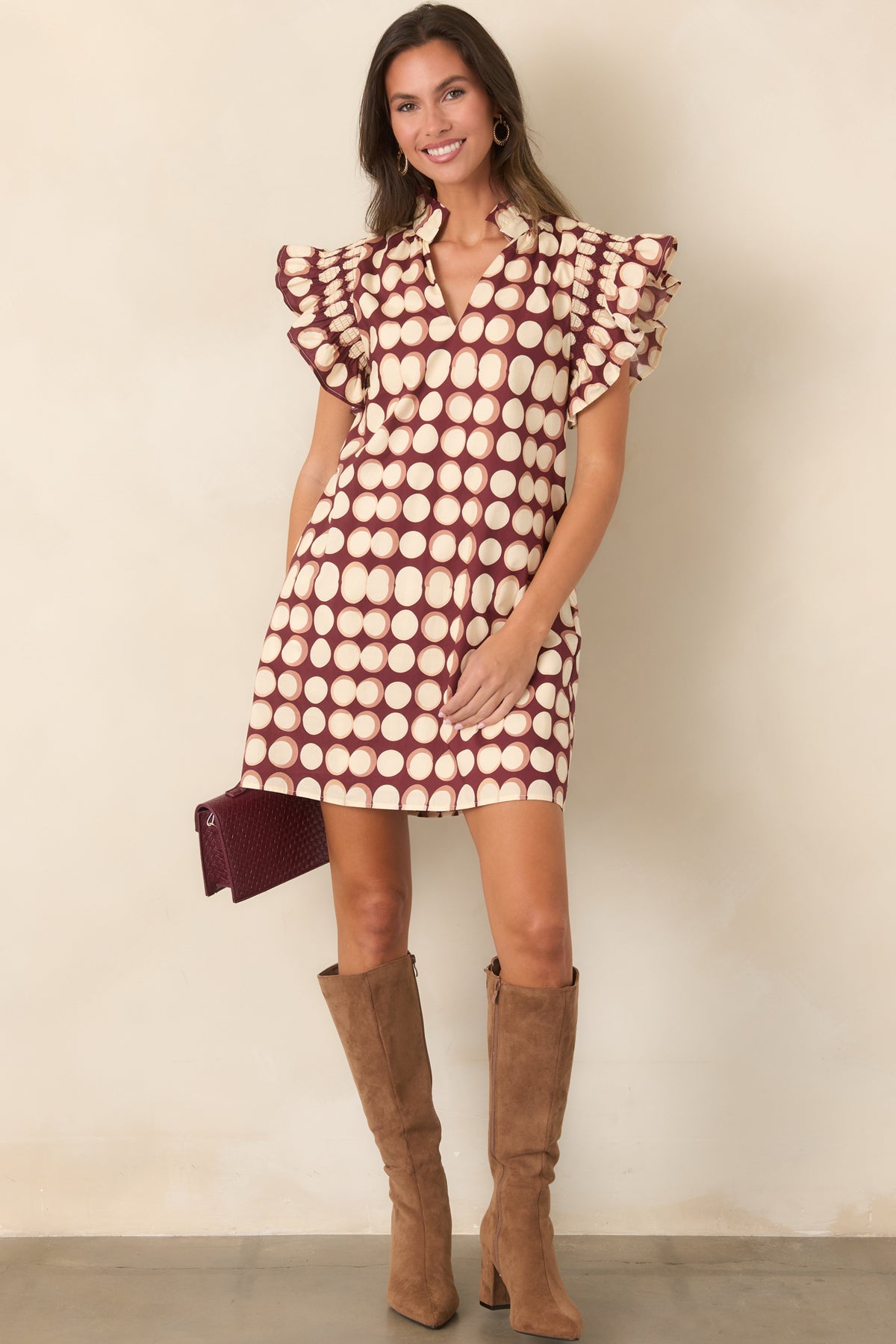 Ivory dot patterned burgundy mini dress featuring a ruffled stand collar, short flutter sleeves, and an uncomplicated pull-on design.
