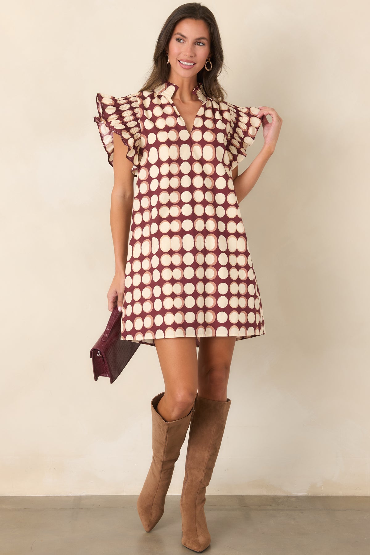 Burgundy cotton mini dress showcasing oversized ivory dots, a romantic ruffled collar, short flutter sleeves, and relaxed shift styling.