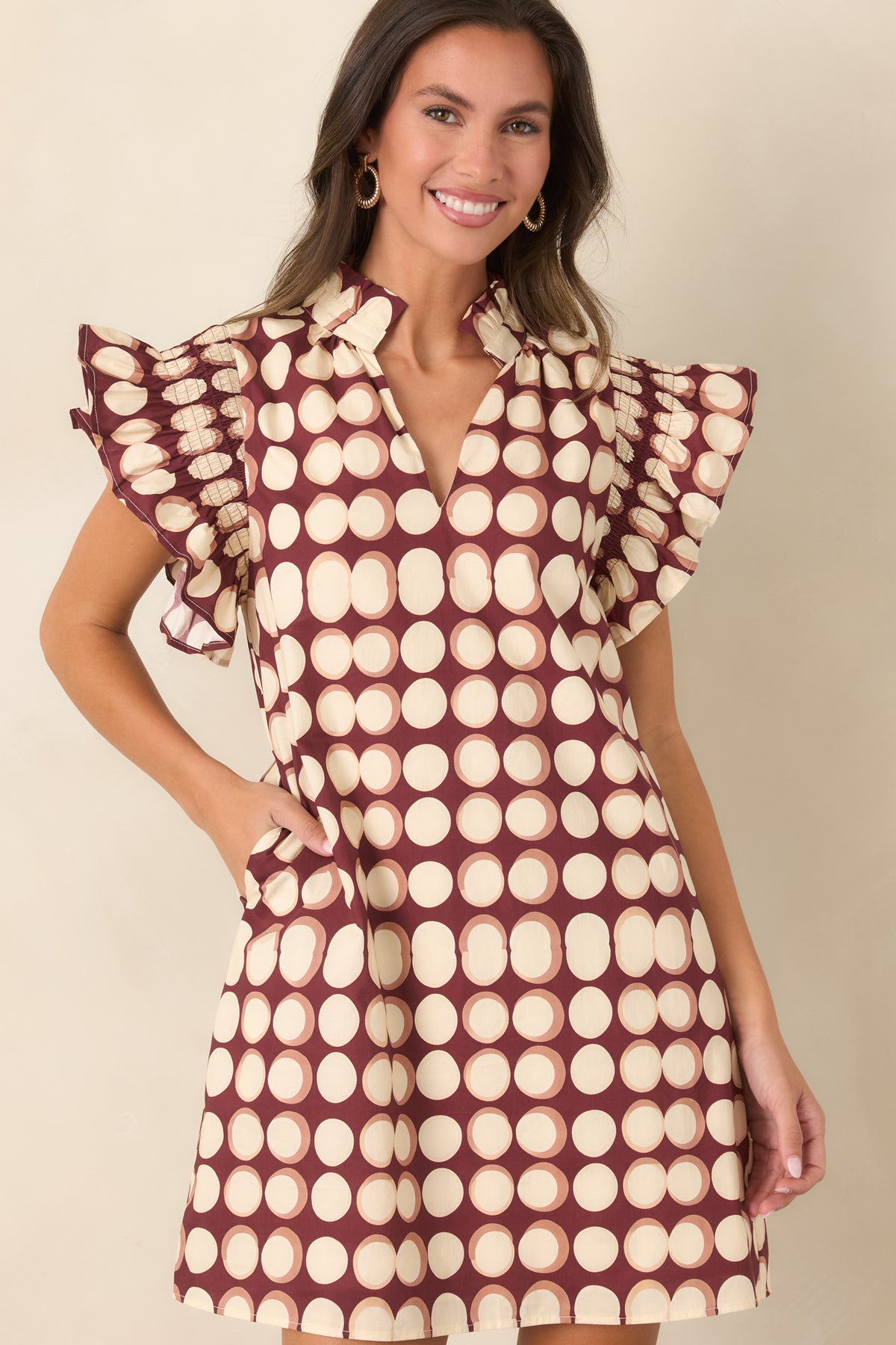 Burgundy dress with oversized ivory dots, split neckline, ruffled stand collar, and gathered flutter sleeves with ruffled edges.