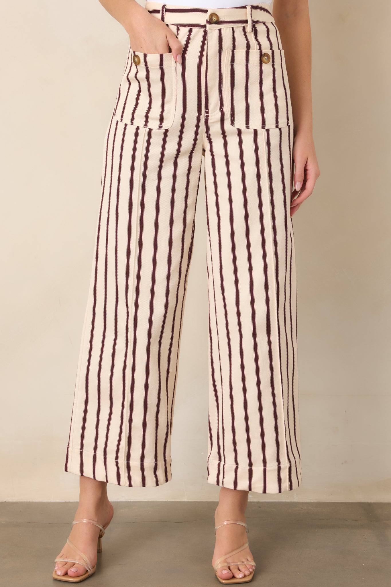 Burgundy and ivory striped pants highlighting the high-rise waist, oversized patch pockets, decorative buttons, and belt loops.